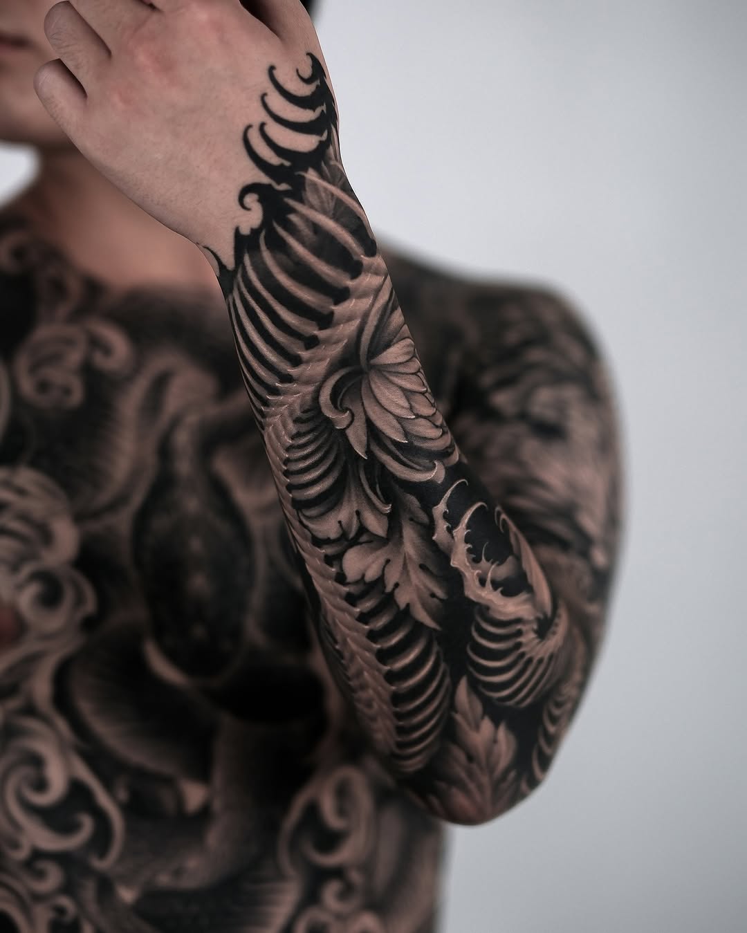 Rib cage and floral elements realism tattoo on the upper arm by Yujin Ju