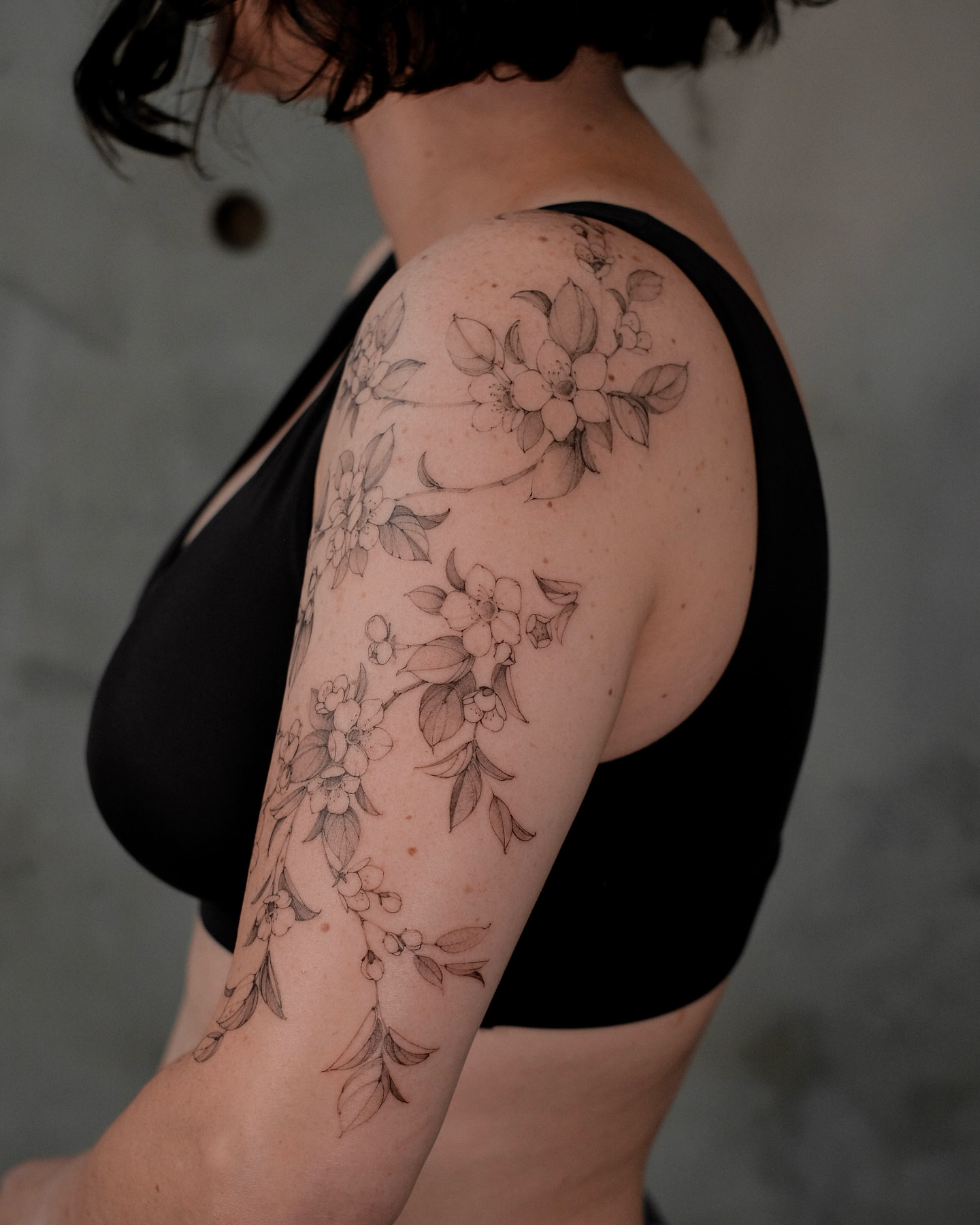 Floral vine black and grey tattoo on the upper arm by Mary Shekh