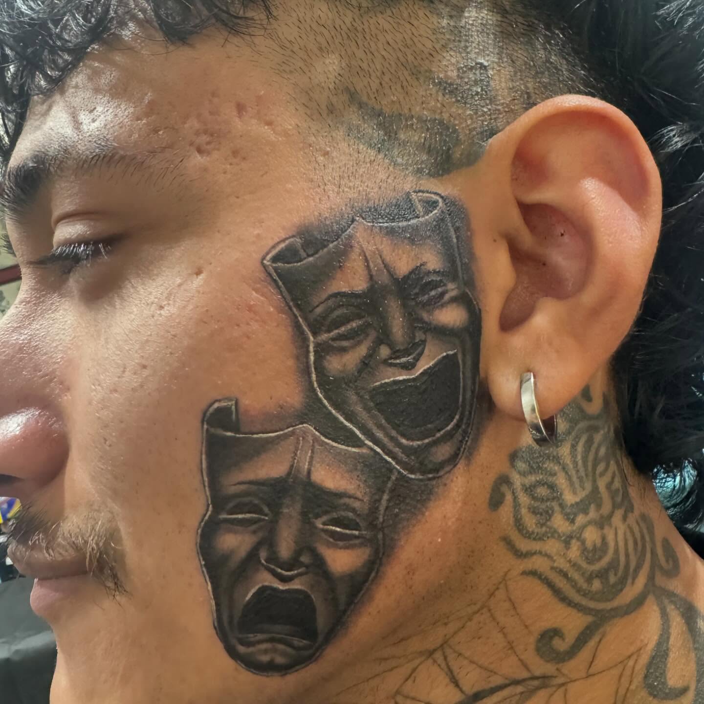 Theater masks black and grey tattoo on the neck by Wolf of Wall St.