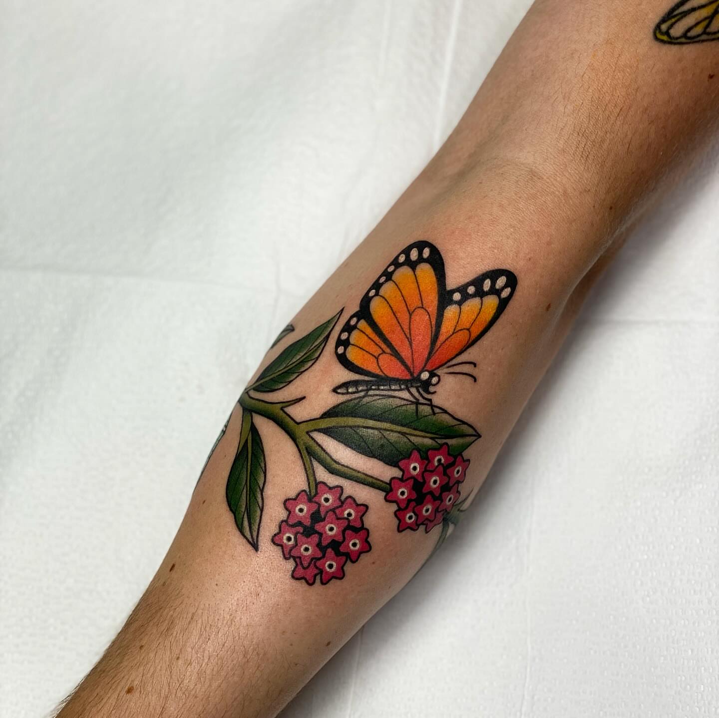 Monarch butterfly and flowers American traditional tattoo on the forearm by Chelstine, Encinitas, California