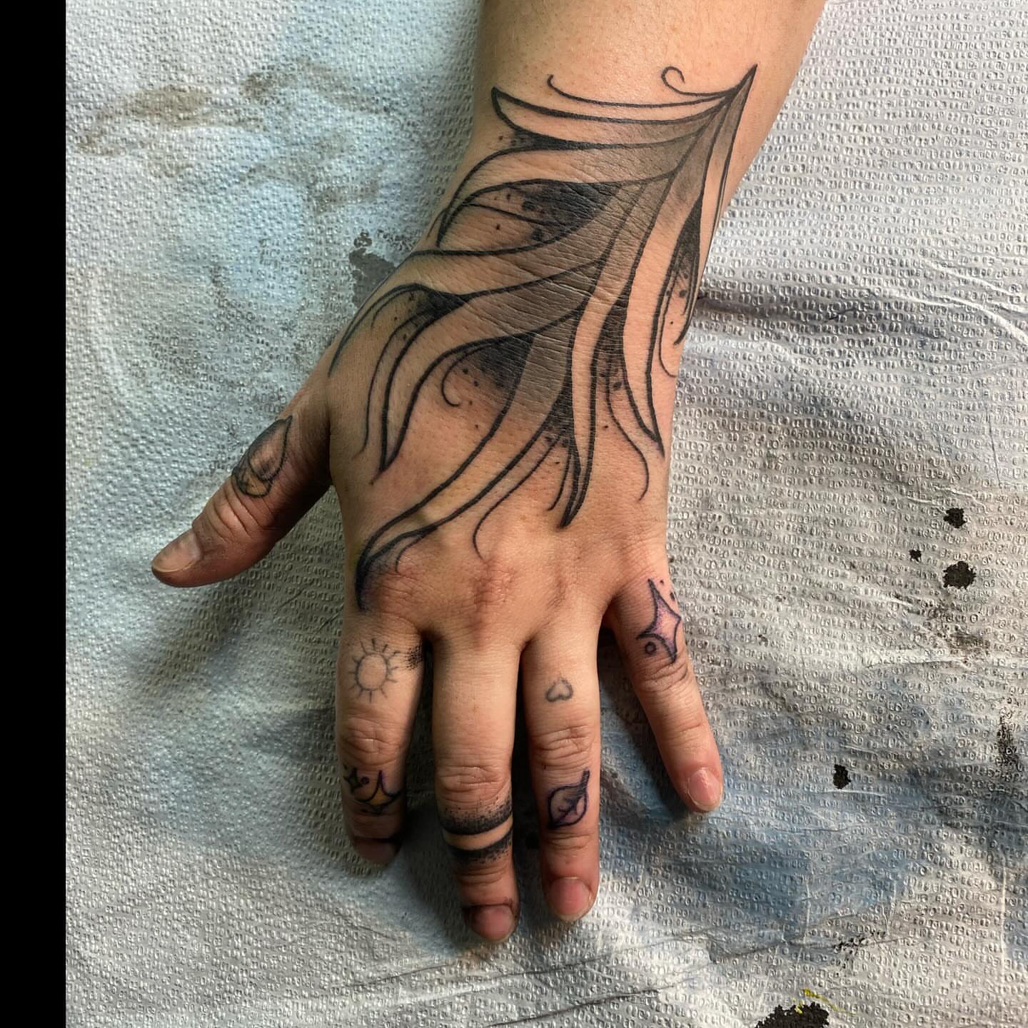 Feather black and grey tattoo on the hand by Shelby Warren