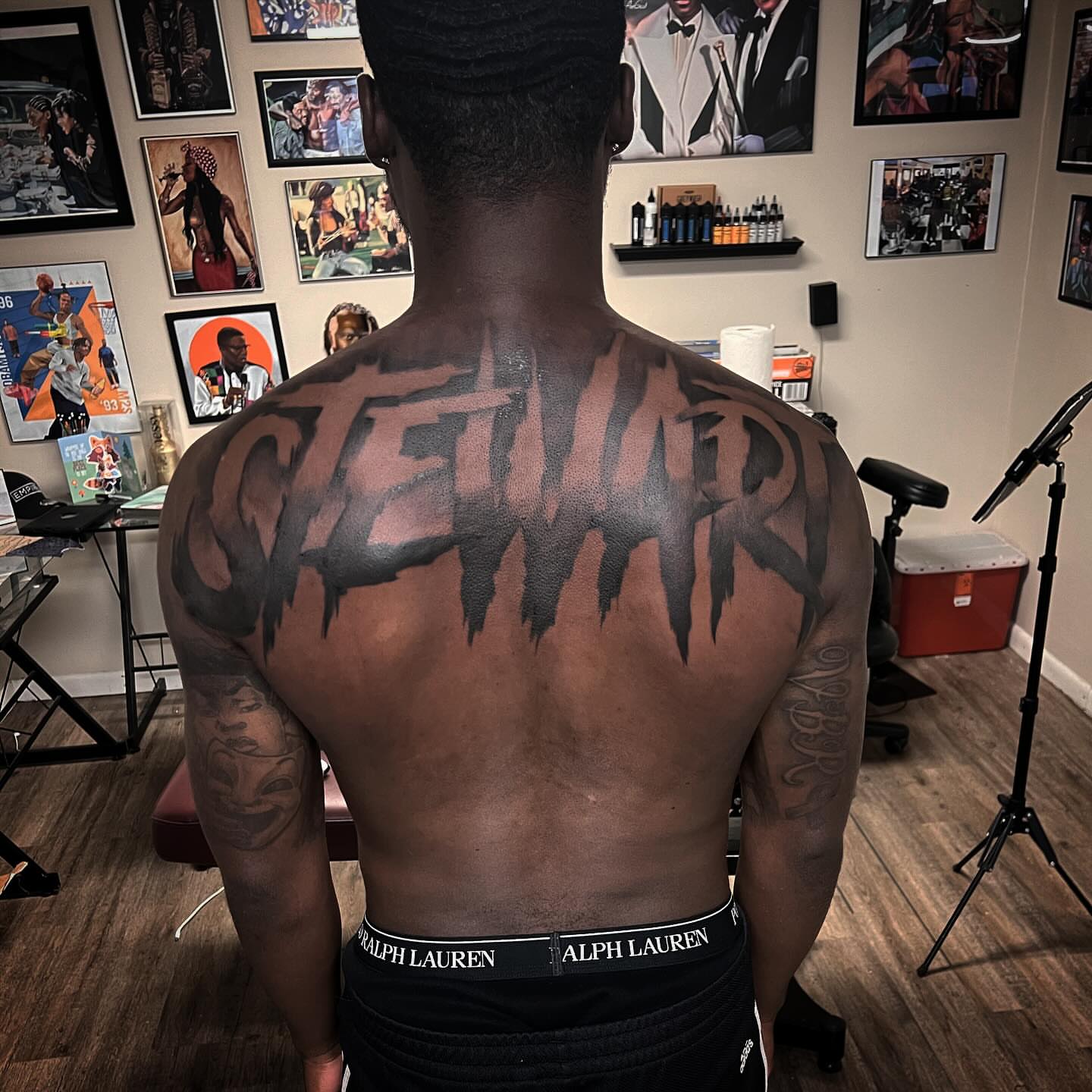 Stencil-style lettering lettering script tattoo on the back by Jared McGee
