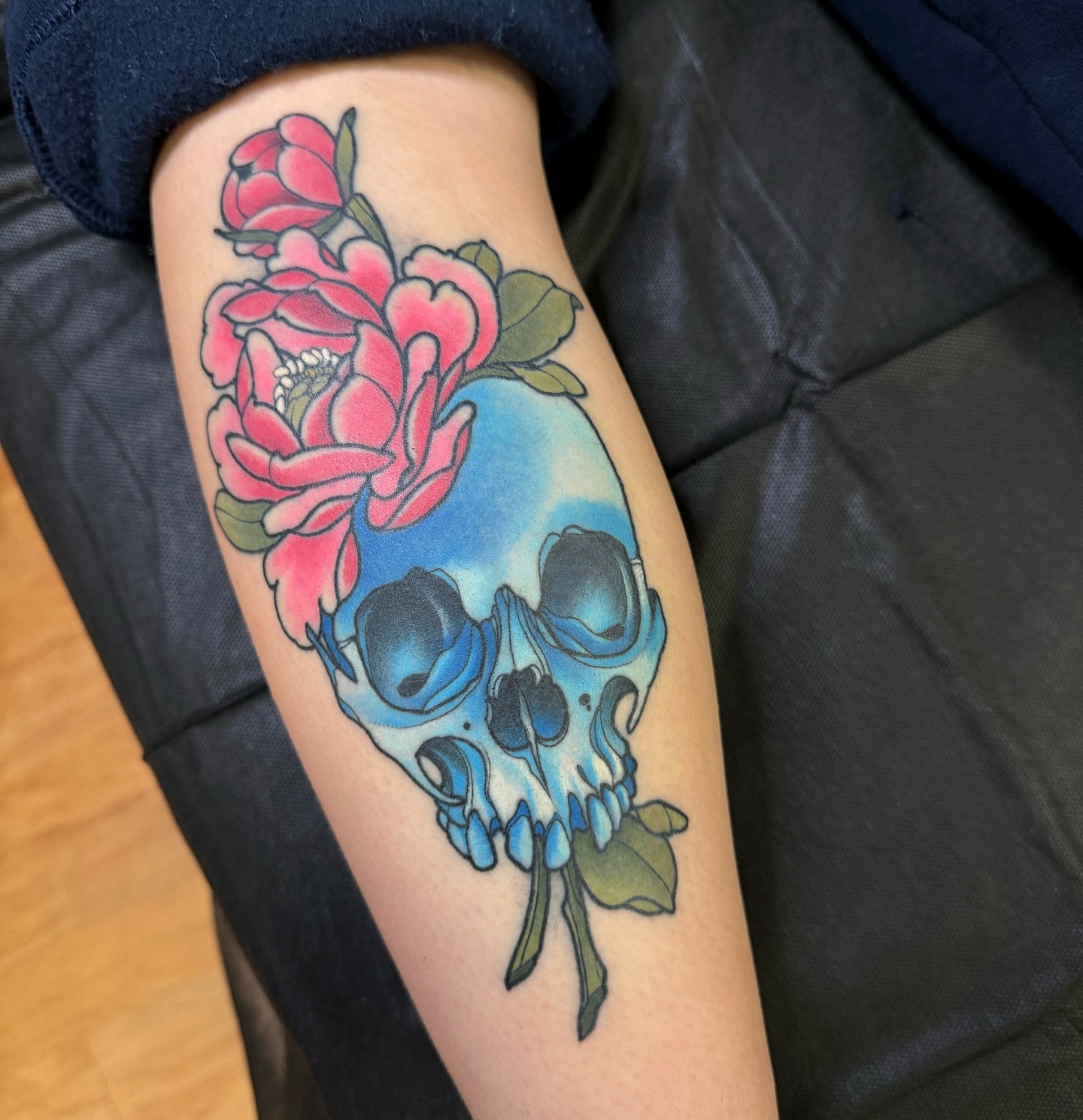 Skull and flowers American traditional tattoo on the forearm by Anne Cornelson