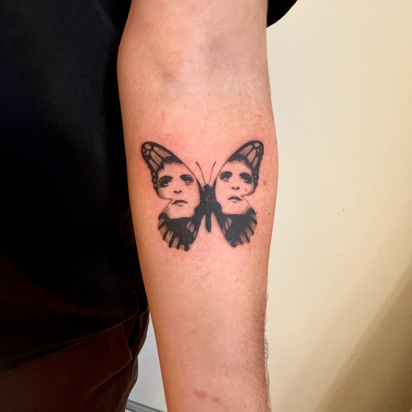Butterfly faces black and grey tattoo on the forearm by Maddy Paige