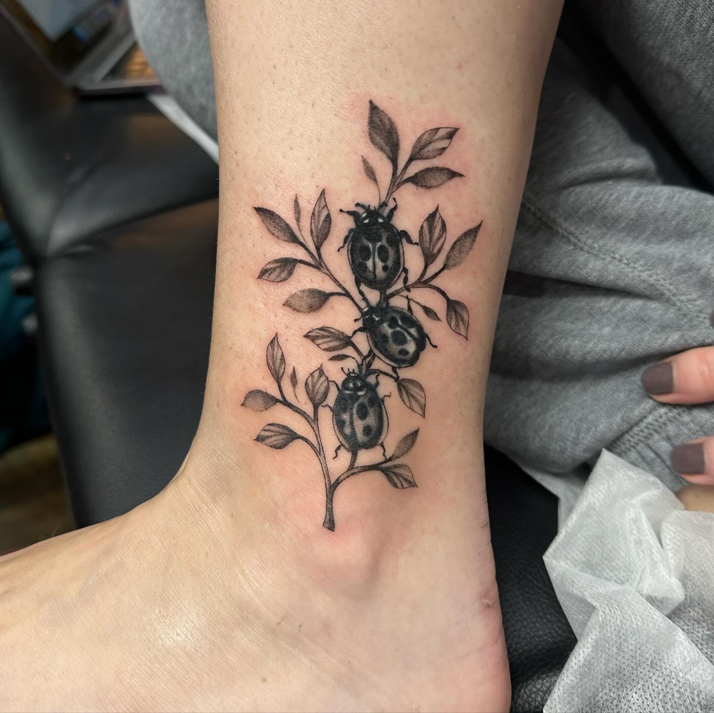 Ladybugs and leaves black and grey tattoo on the forearm by Emmy