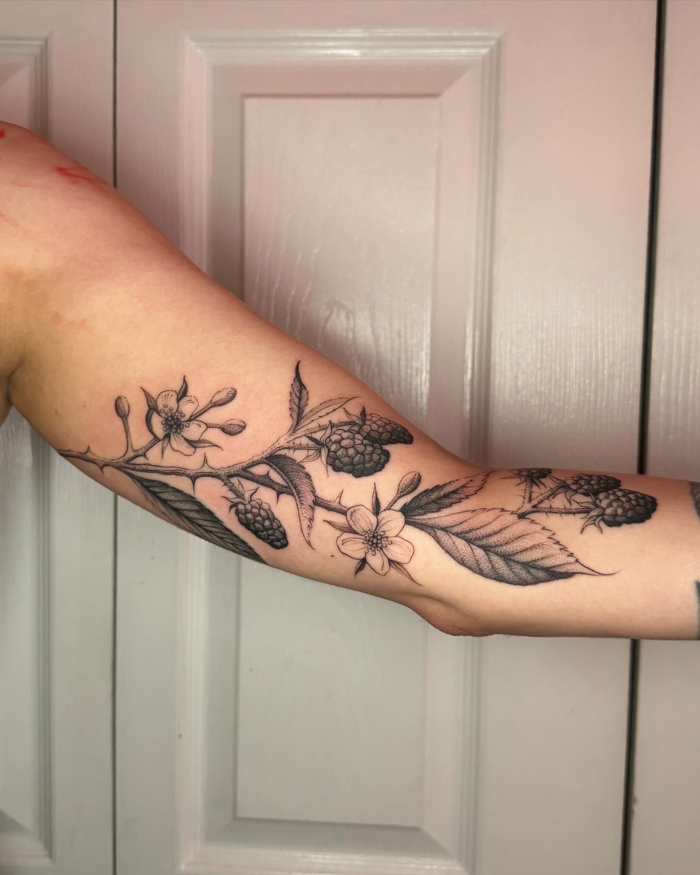 Flower and berries black and grey tattoo on the forearm by Natasha