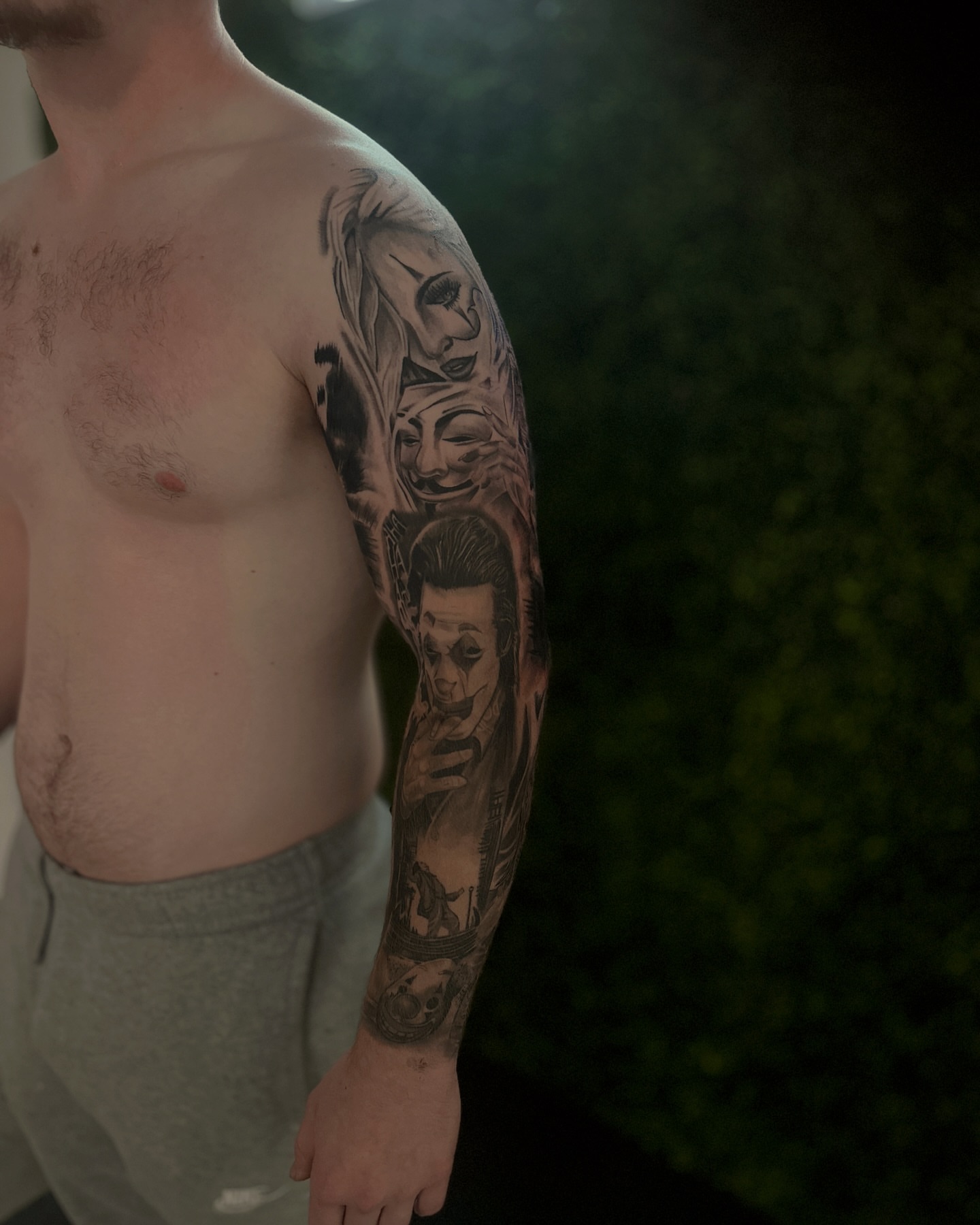 Clowns black and grey tattoo on the upper arm by ᴡᴏʀᴍ