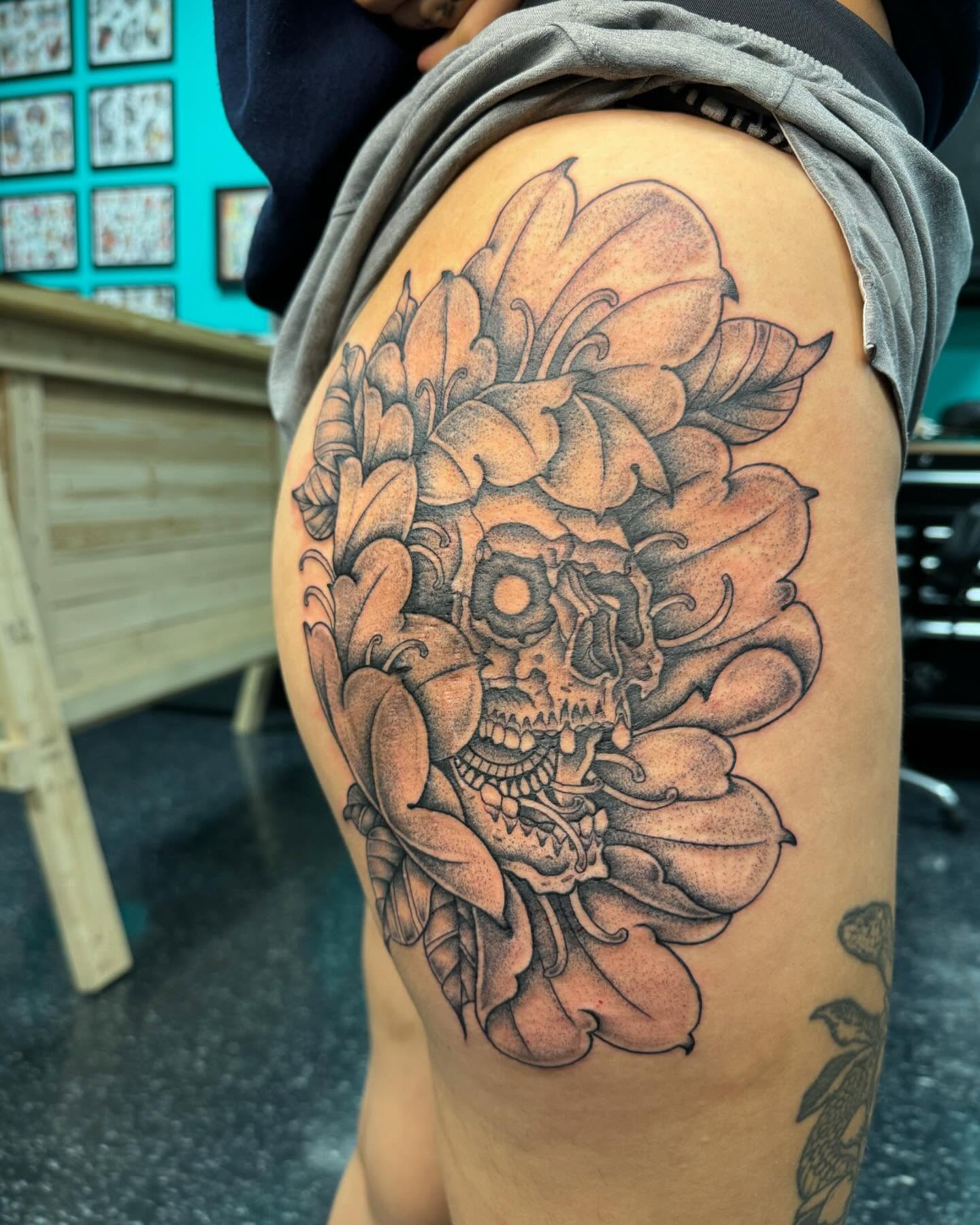 Skull and floral realism tattoo on the thigh by Cory Perry-Servellon