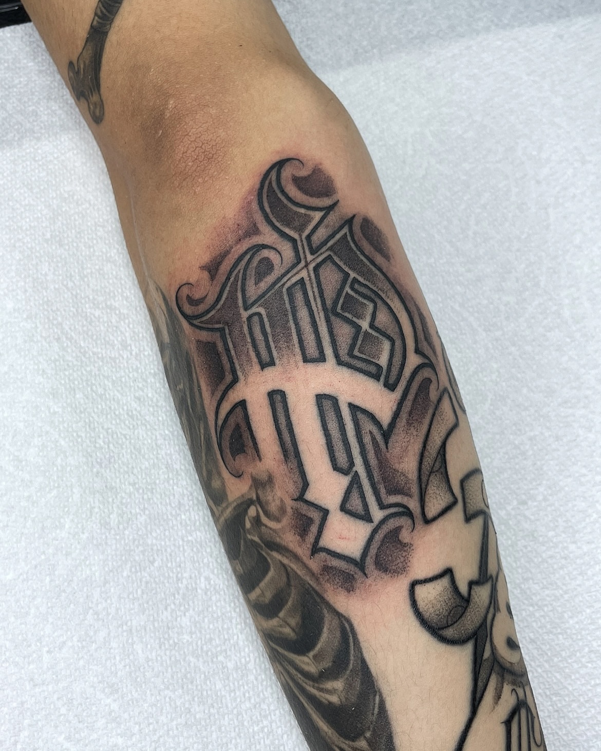 Lettering black and grey tattoo on the forearm by Joon 치카노레터링