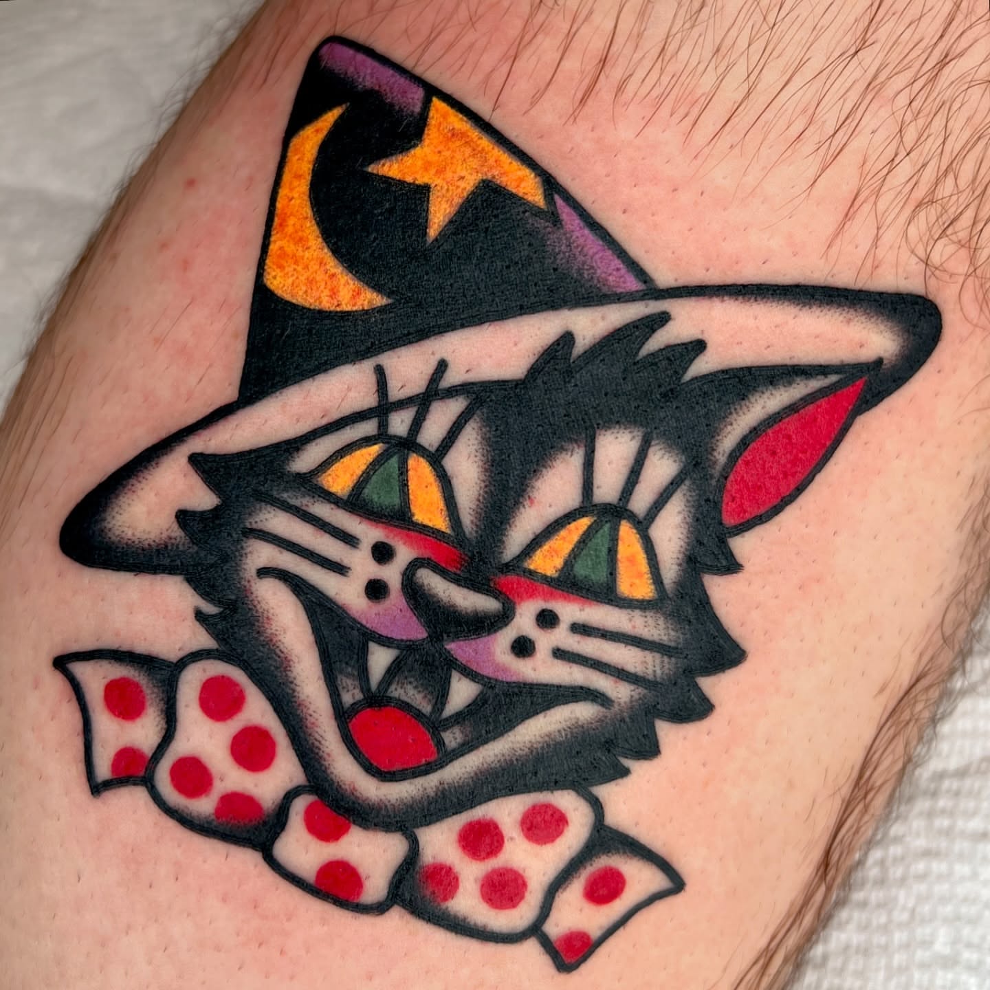 Cat wearing hat American traditional tattoo on the upper arm by Ian Jett