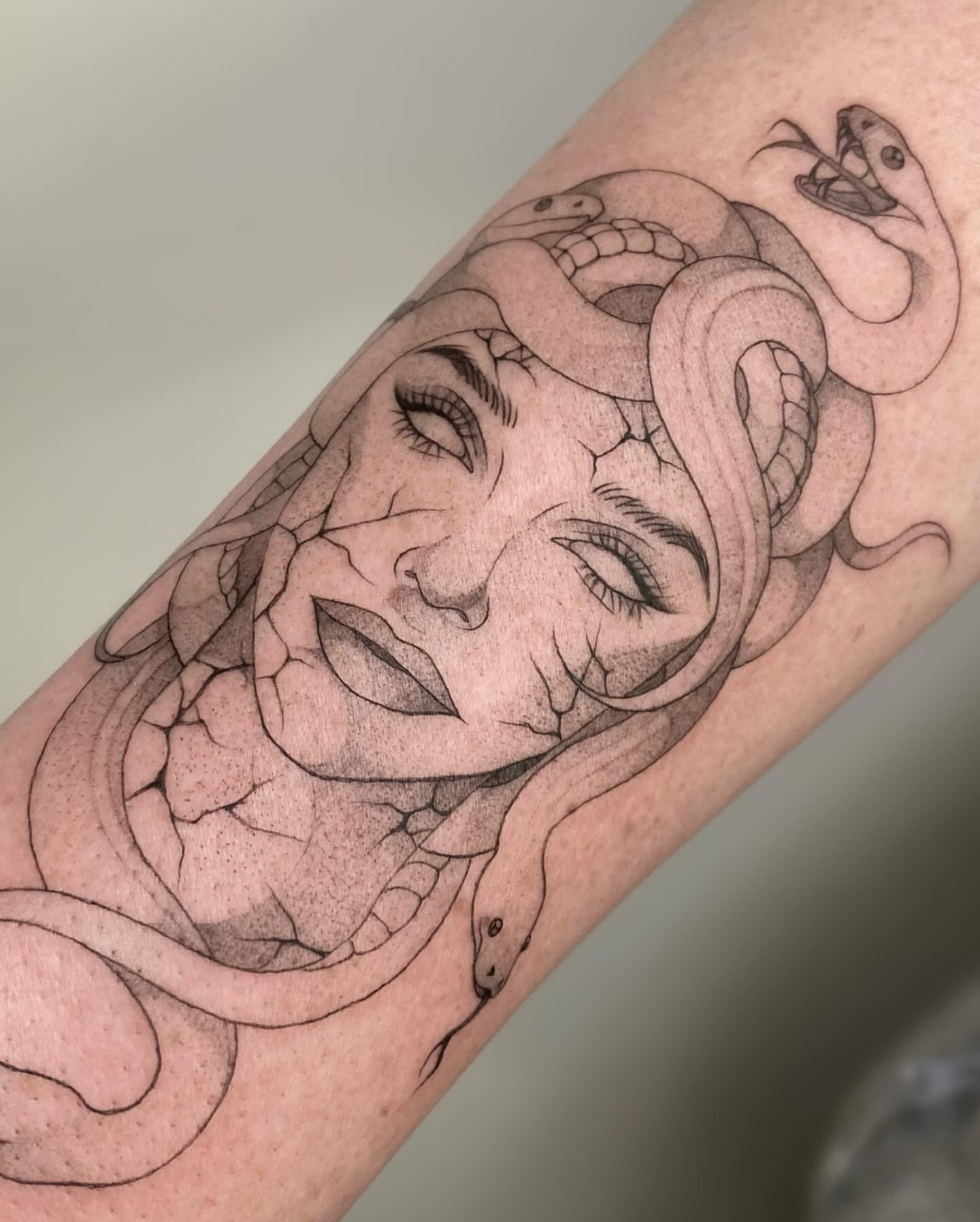 Woman with snakes geometric tattoo on the forearm by seattle tattoo artist