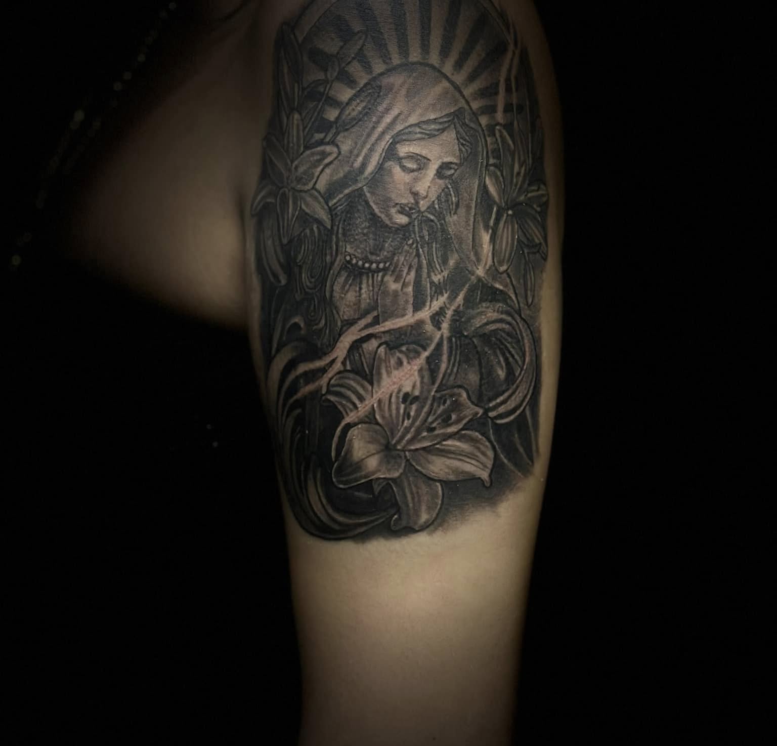 Religious figure with lilies realism tattoo on the forearm by Aj Negrete Jr.