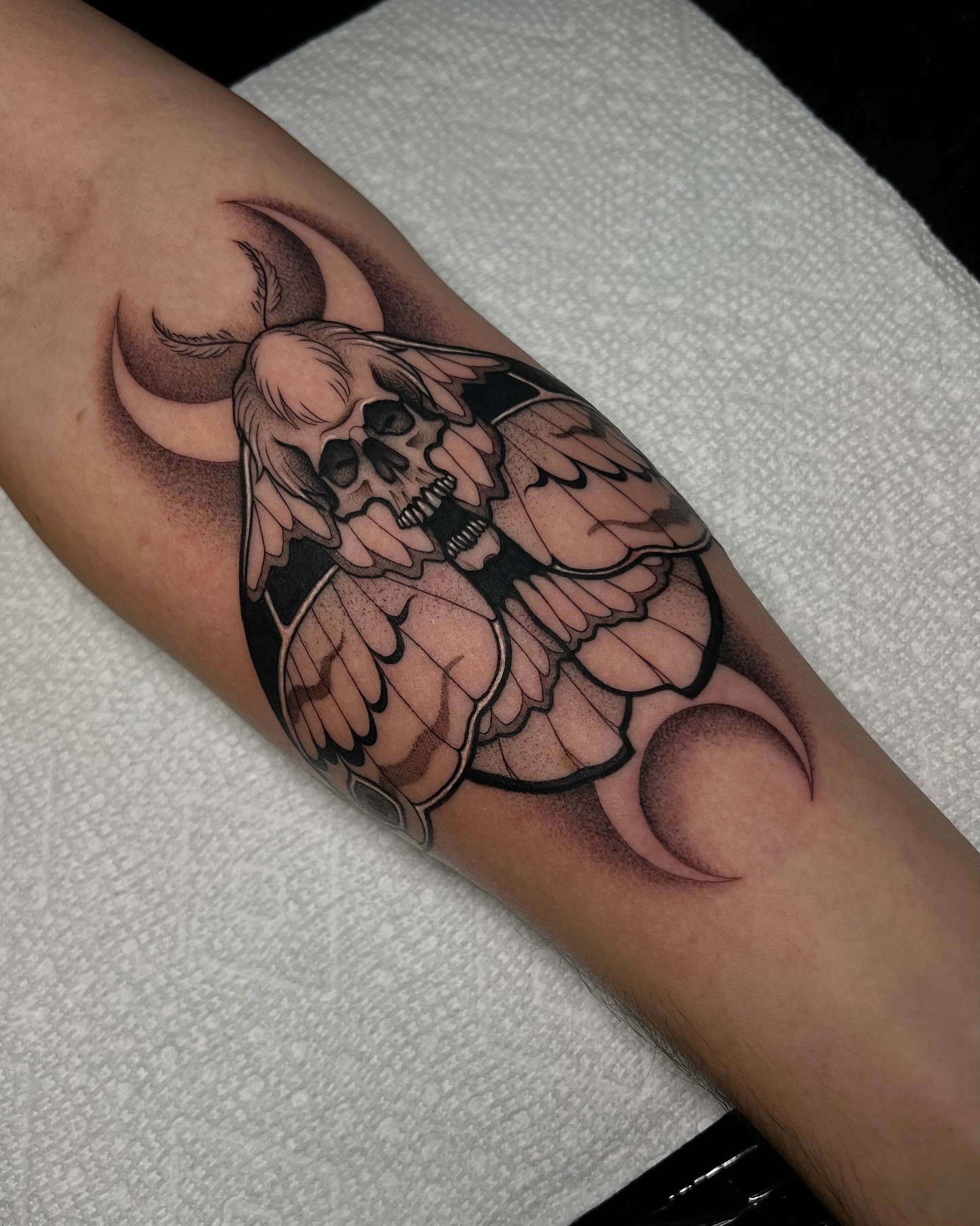 Winged skull black and grey tattoo on the forearm by Bell Bolton