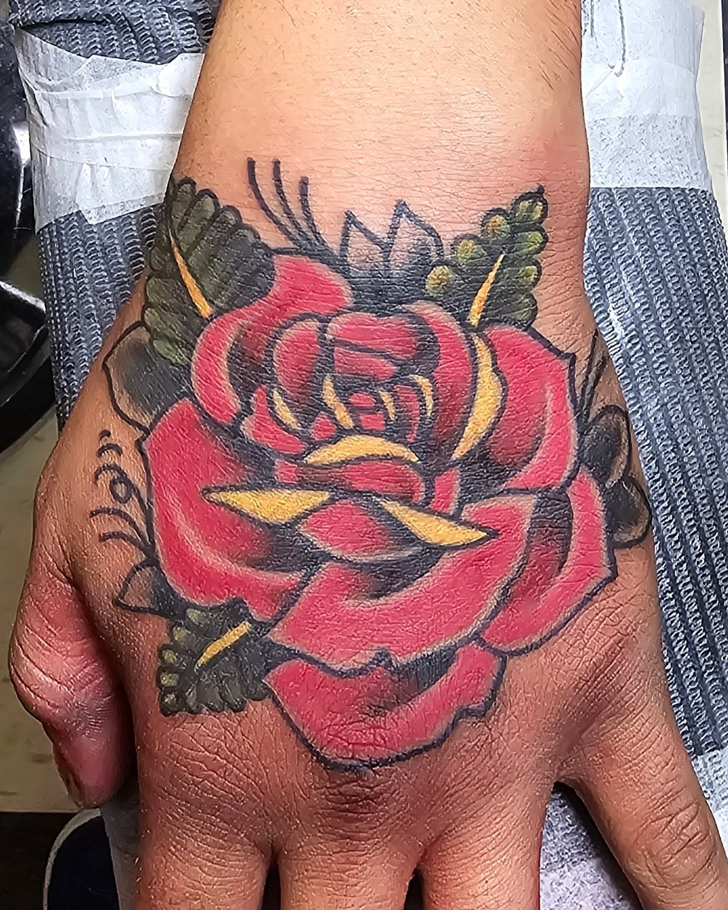 Red rose American traditional tattoo on the hand by Don Robison