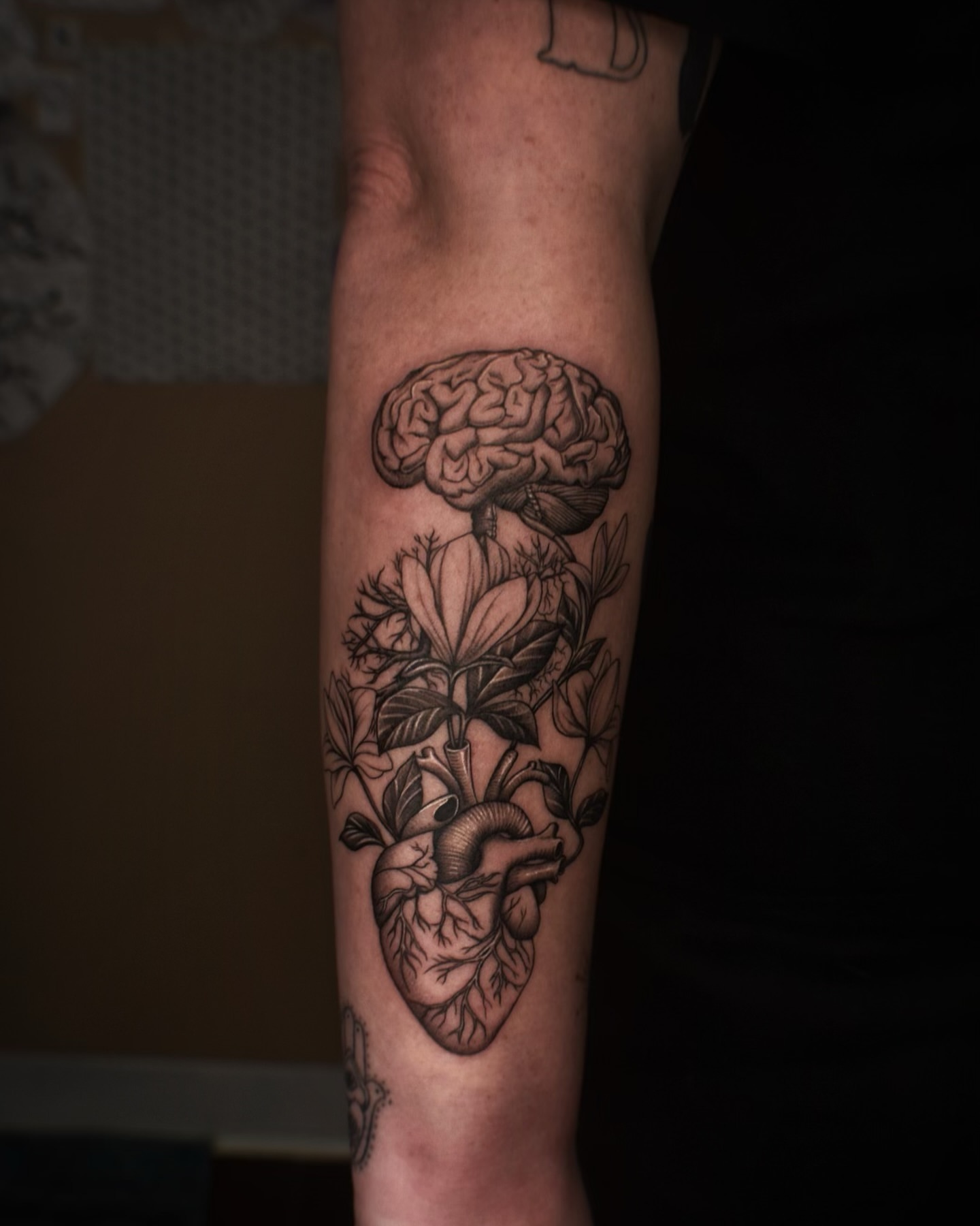 Brain and heart with floral elements realism tattoo on the forearm by Alexandria Gudiel