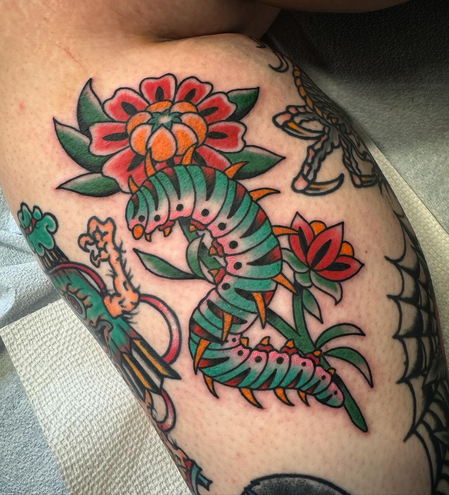 Centipede and flowers American traditional tattoo on the thigh by Ethan Bennett