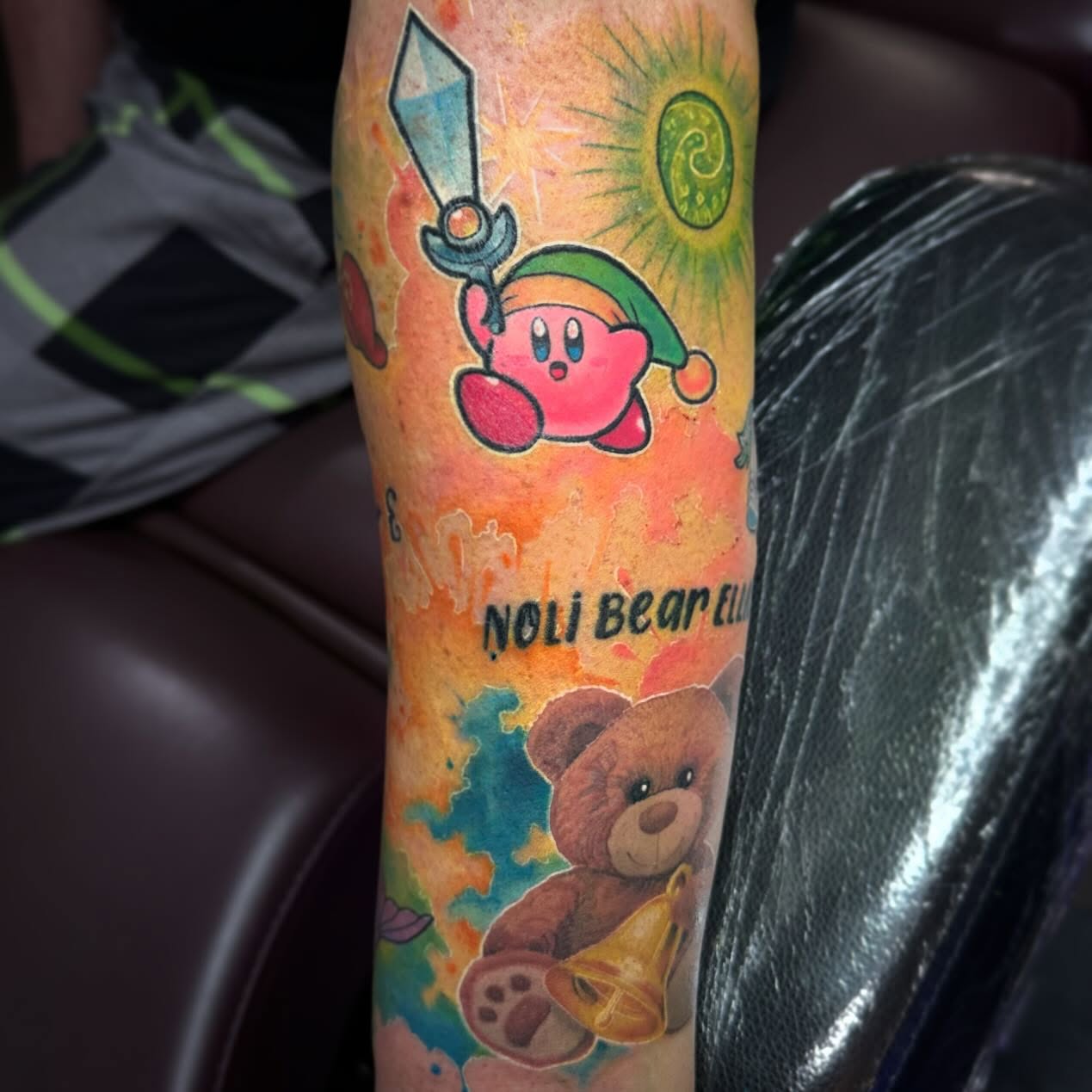 Kirby and teddy bear watercolor tattoo on the forearm by Oscar Arias