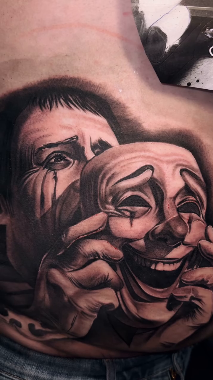 Two masks, one crying, one laughing realism tattoo by Tattoo
