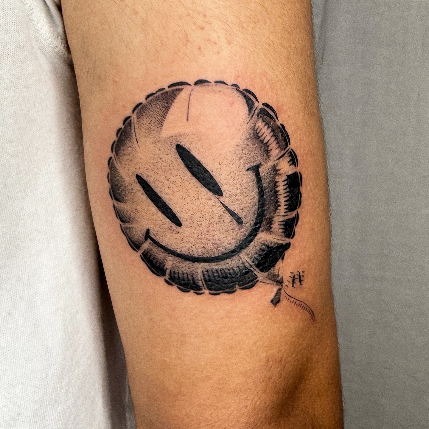 Smiley face black and grey tattoo on the forearm by Jenni Palomaa