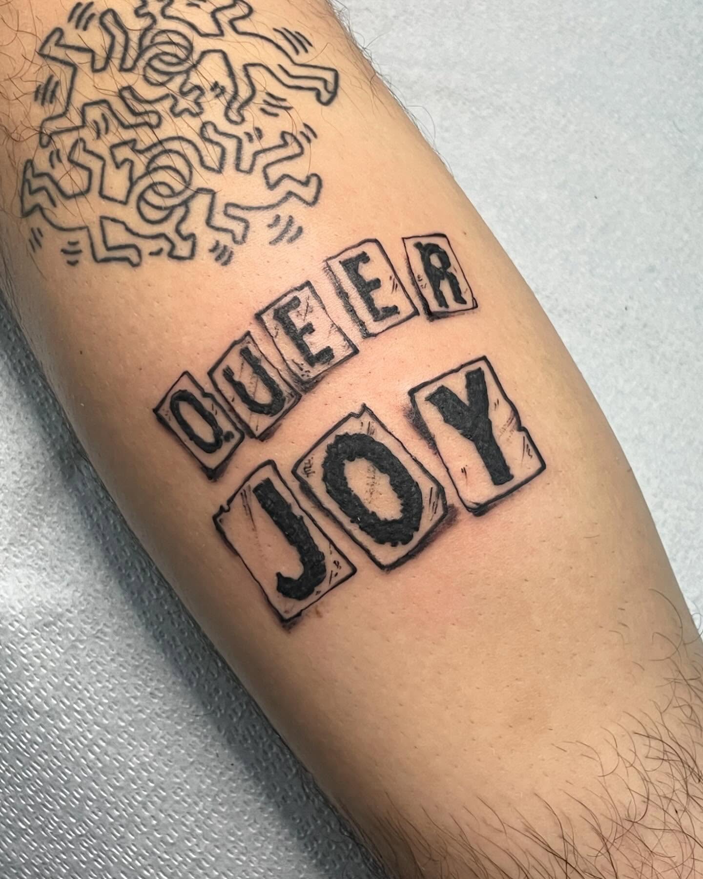 Queer joy black and grey tattoo on the forearm by G. Clover ⚧︎, Chicago, Illinois
