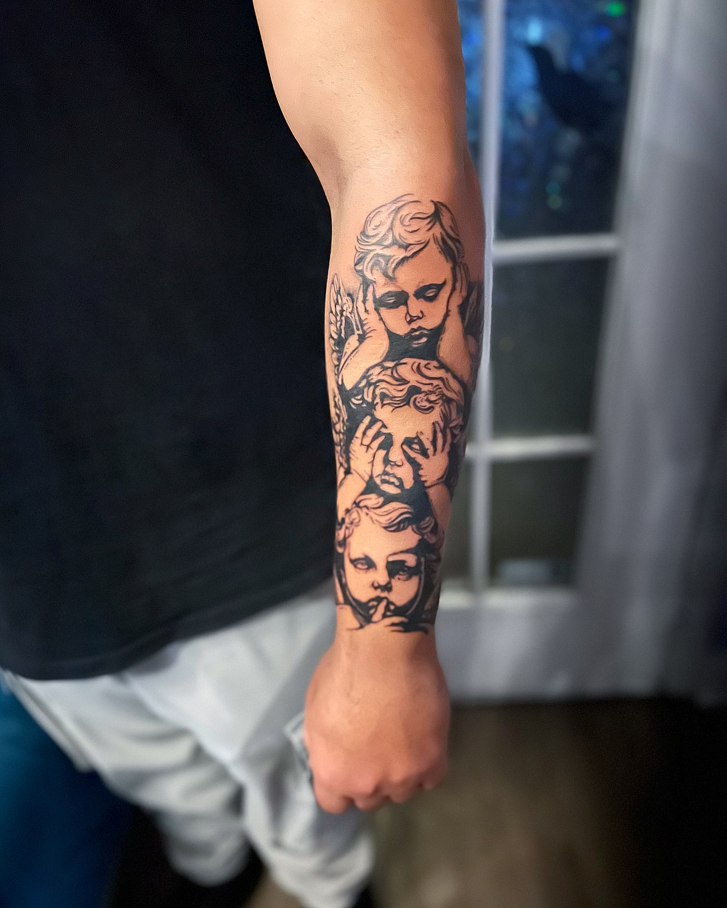 Cherubs black and grey tattoo on the forearm by Rose DeLisse