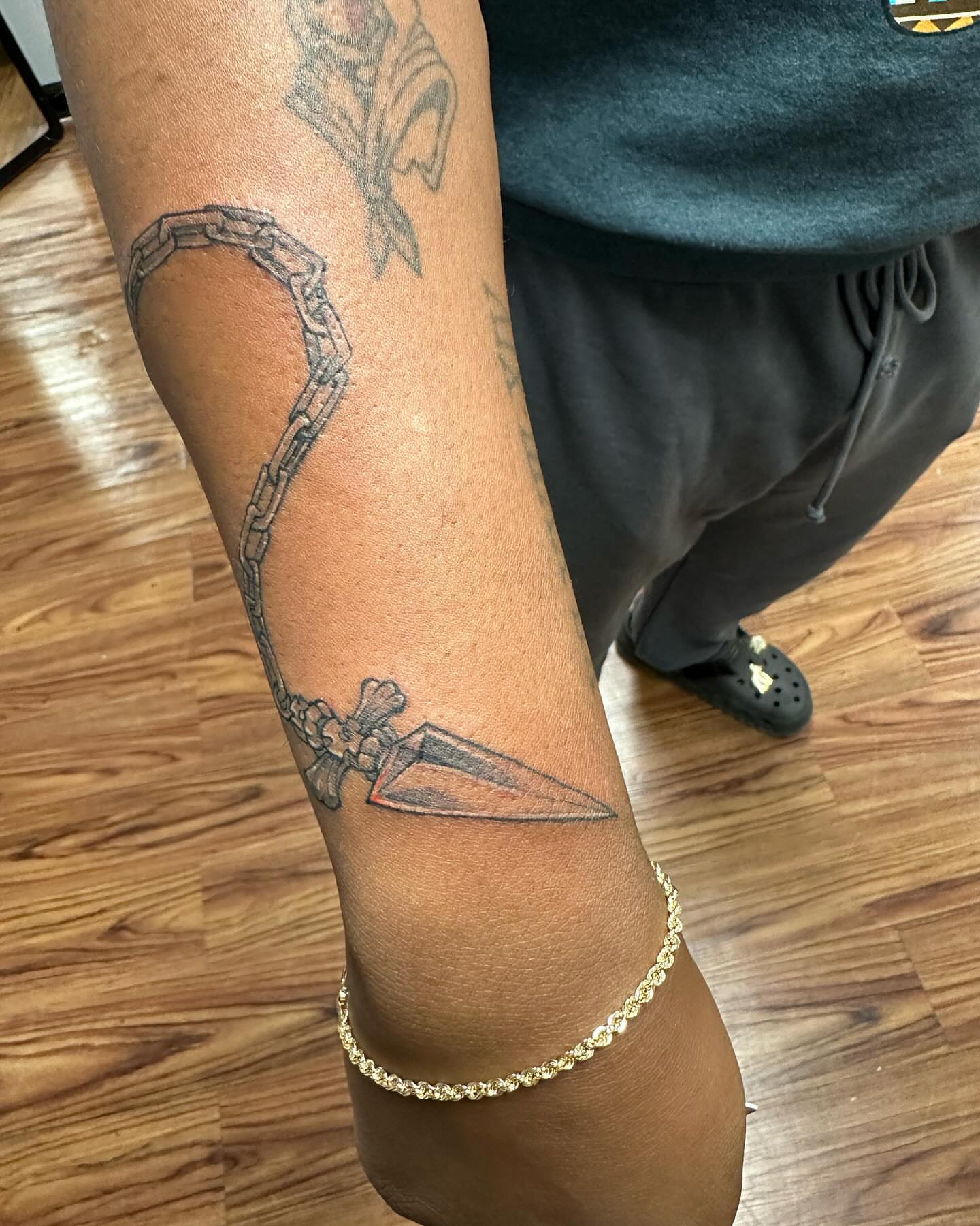 Knife and chain black and grey tattoo on the forearm by Jan Xander