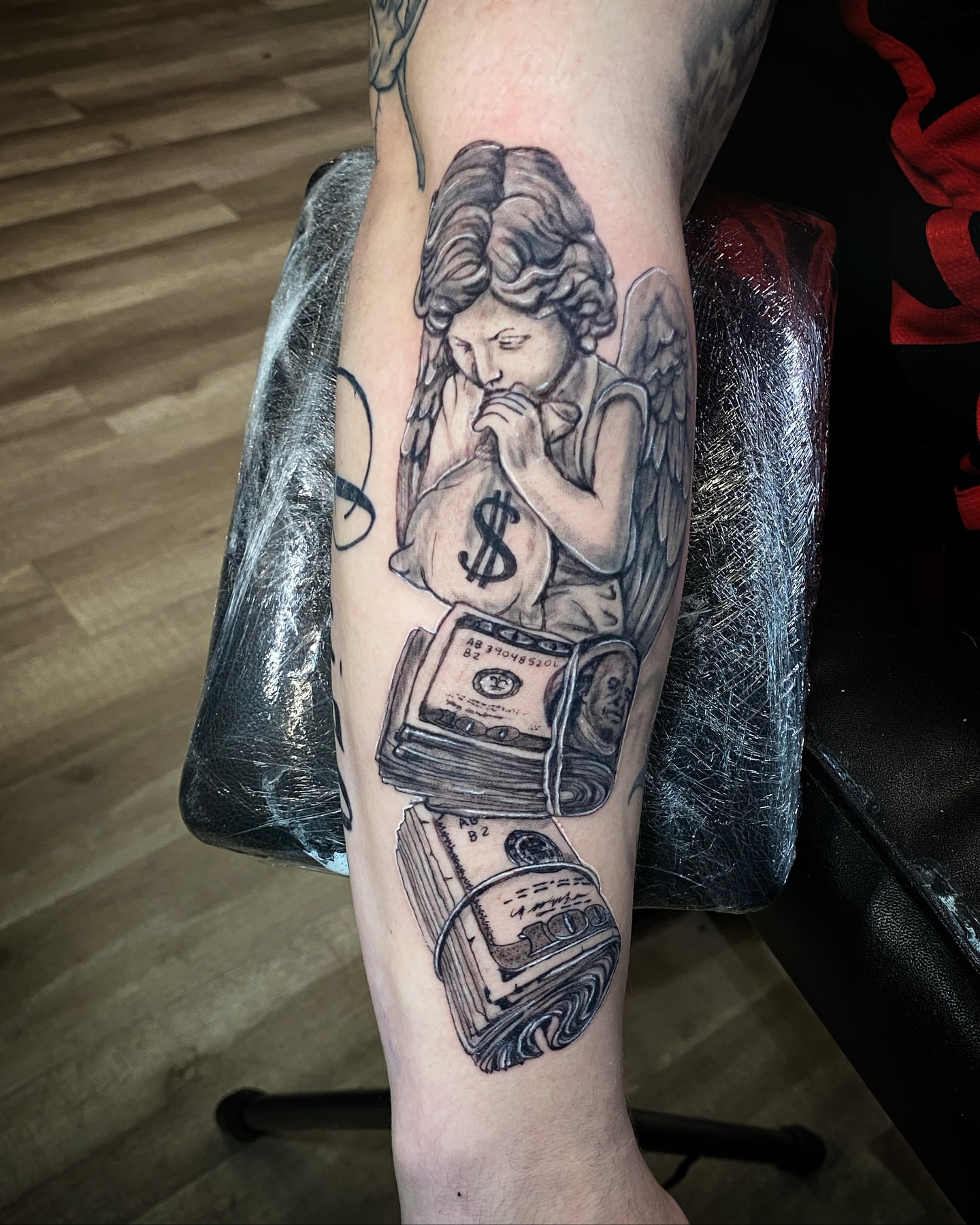 Angel with money realism tattoo on the forearm by Erasmo Vasquez
