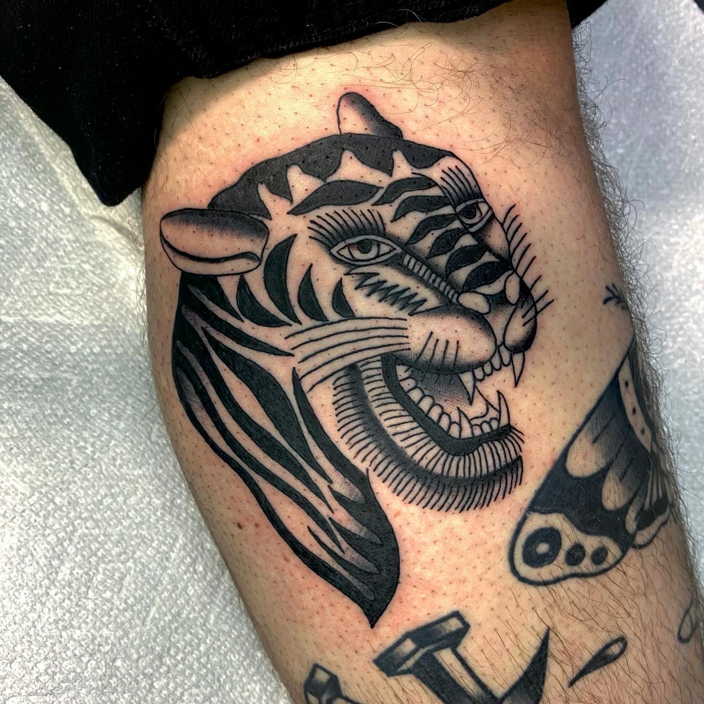 Tiger head black and grey tattoo on the thigh by Shana