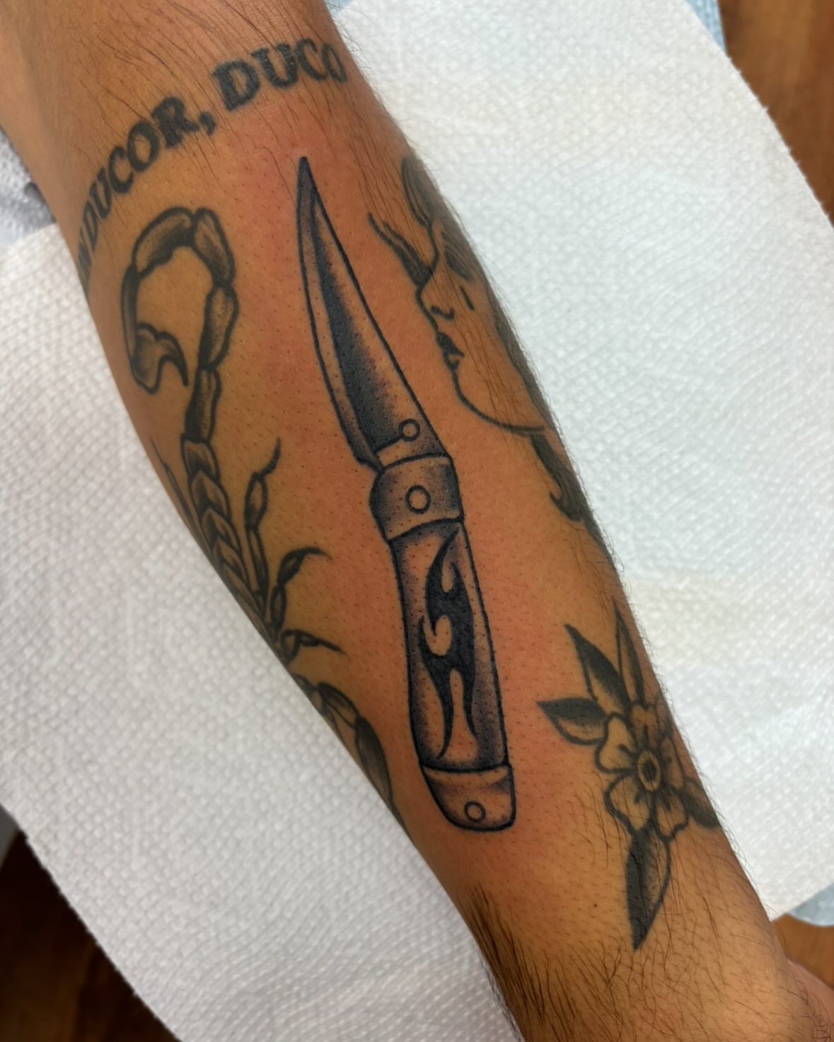 Knife and floral black and grey tattoo on the forearm by ⟡ Sam O ⟡