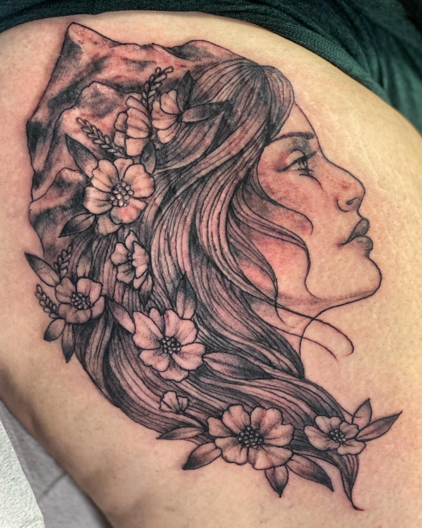 Woman with flowers realism tattoo on the thigh by Tattoos By Trish