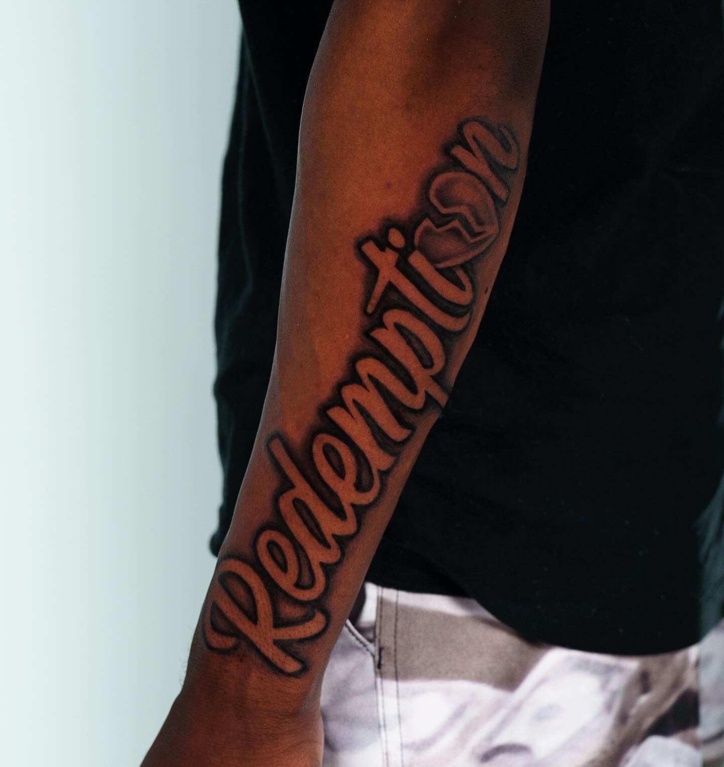 Redemption lettering script tattoo on the forearm by Christopher Heffley
