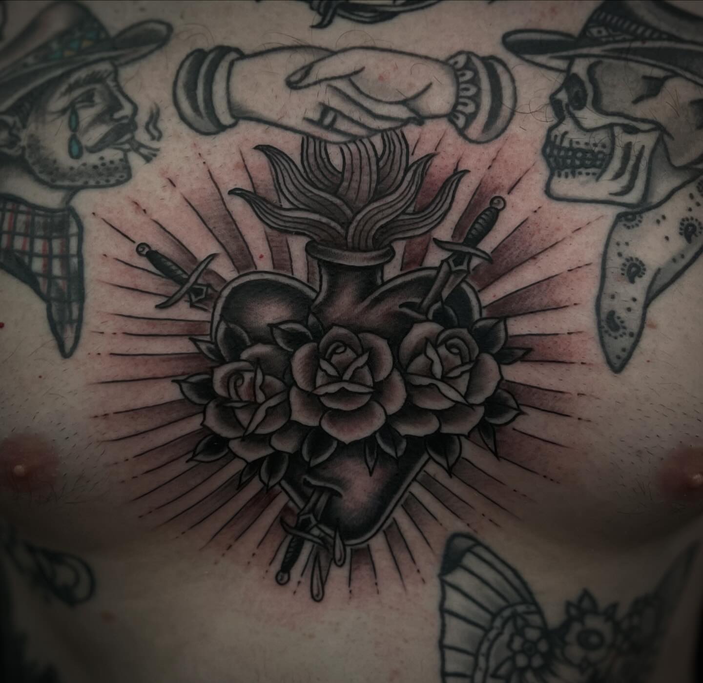 Heart with roses and daggers American traditional tattoo on the chest by Chris Romolini