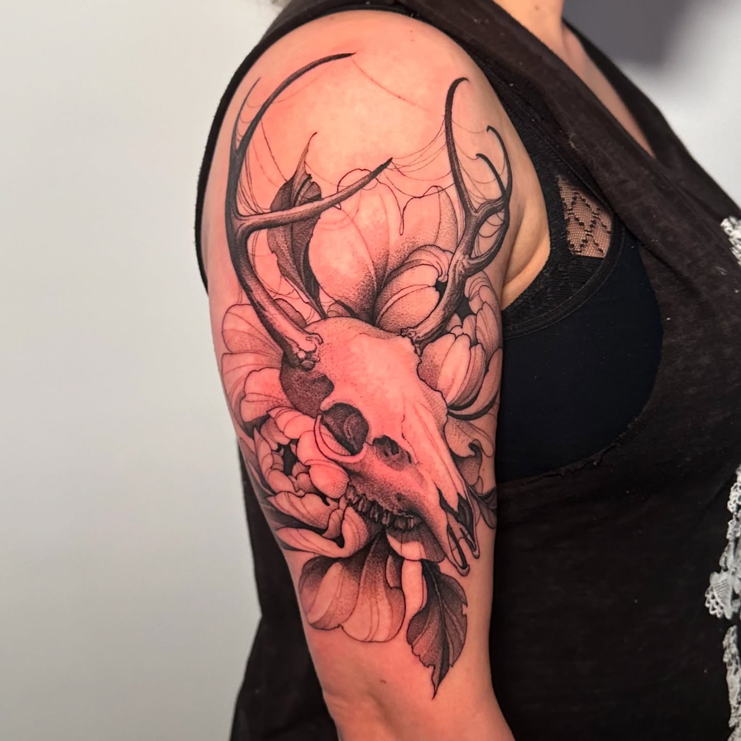 Deer skull with flowers realism tattoo on the shoulder by Strokin Konstantin