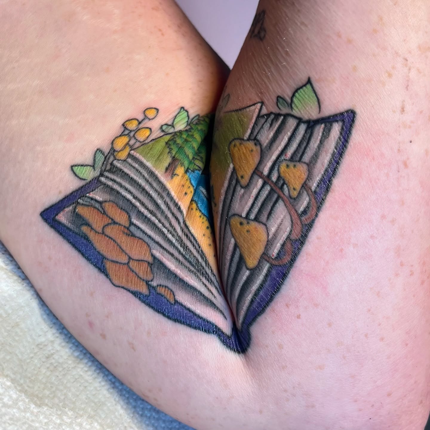 Open book with nature scene geometric tattoo on the thigh by Krystal ✨
