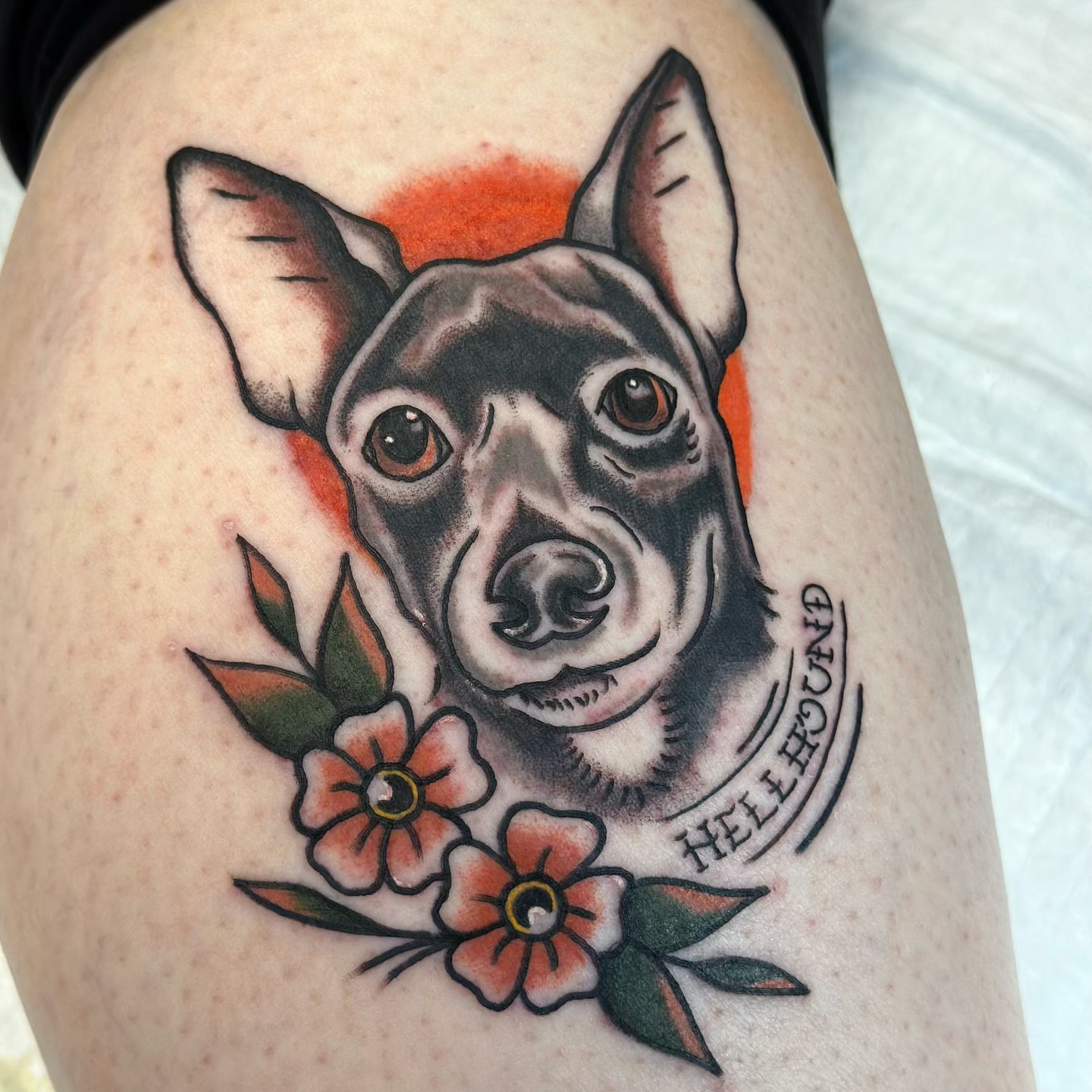 Dog with flowers American traditional tattoo on the thigh by Olive Kelley