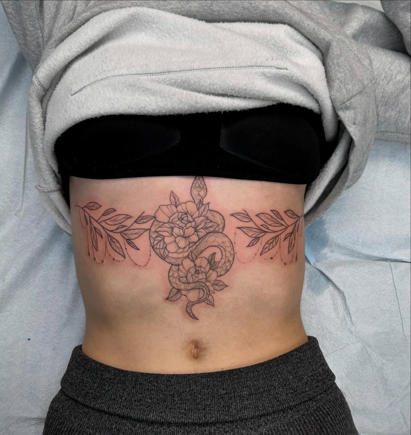Snake and peony black and grey tattoo on the ribs by Amber Lynn