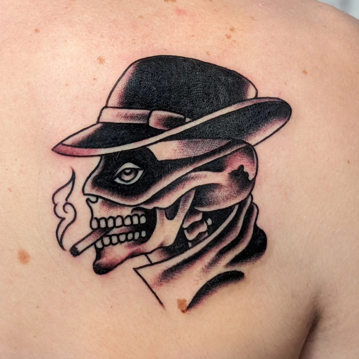 Skull wearing hat American traditional tattoo on the shoulder by Matt Simmonds