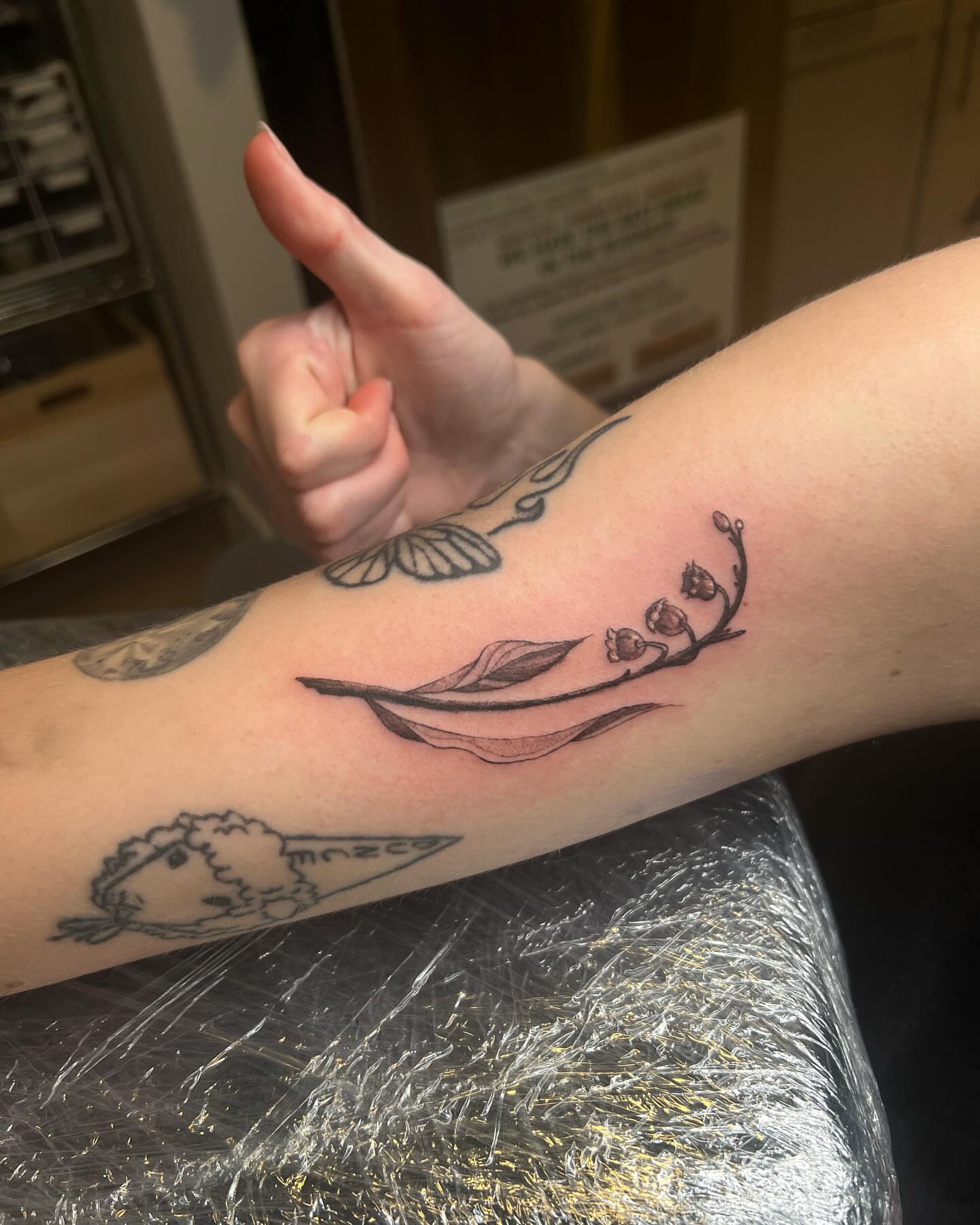 Lily of the valley black and grey tattoo on the forearm by sarah bug