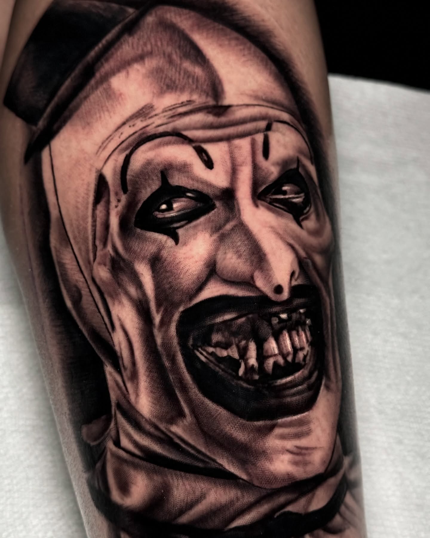 Horror clown realism tattoo on the forearm by Robert Graye
