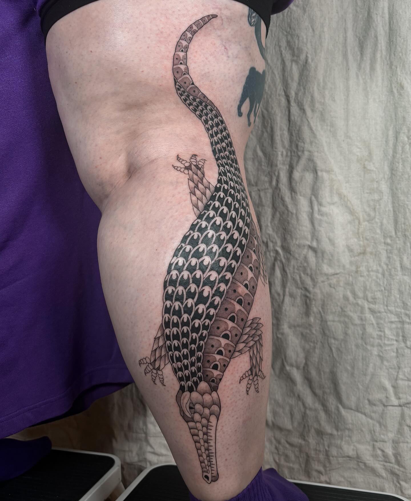 Alligator black and grey tattoo on the thigh by Anna Sage
