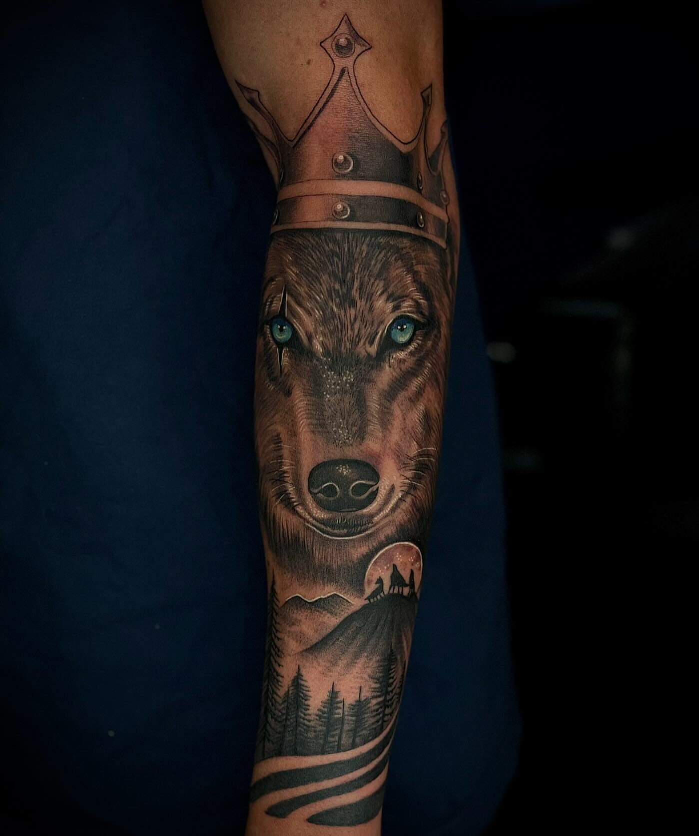 Wolf crown landscape realism tattoo on the forearm by Tam Nguyen