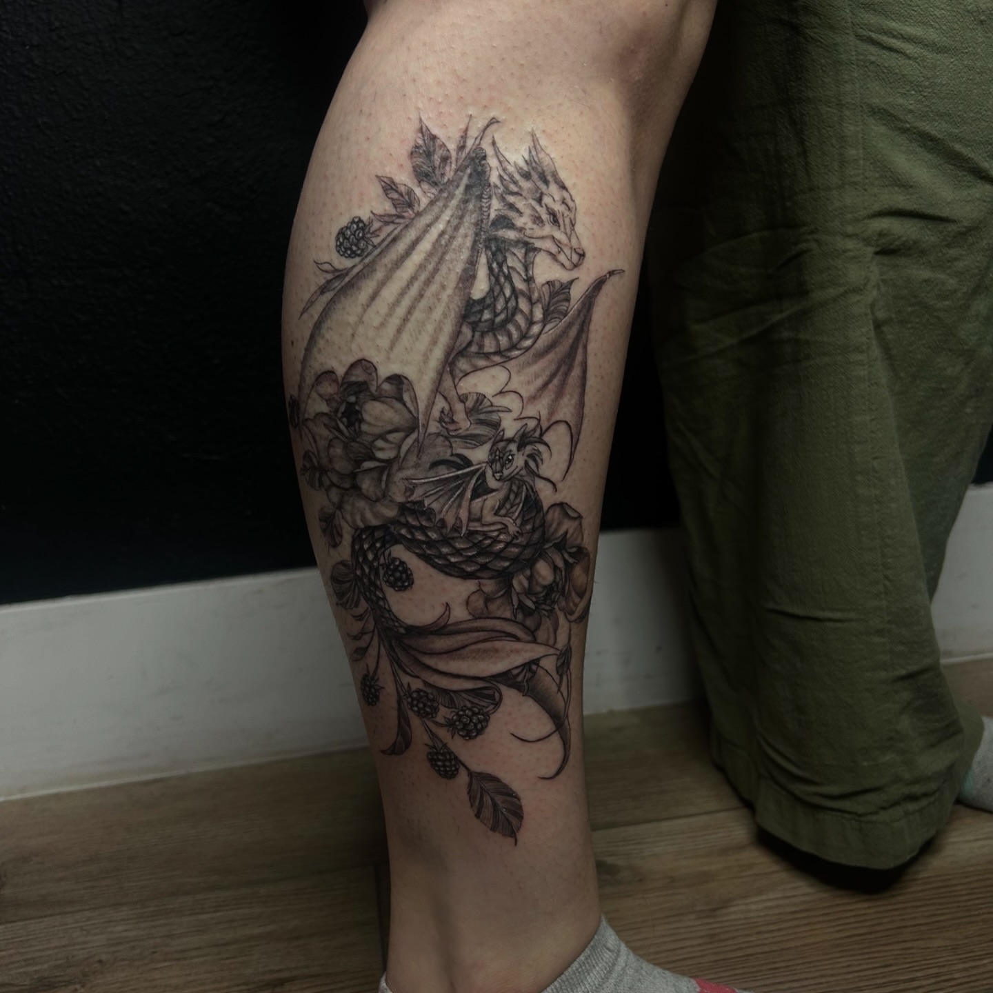 Dragon and flowers realism tattoo on the thigh by Haley