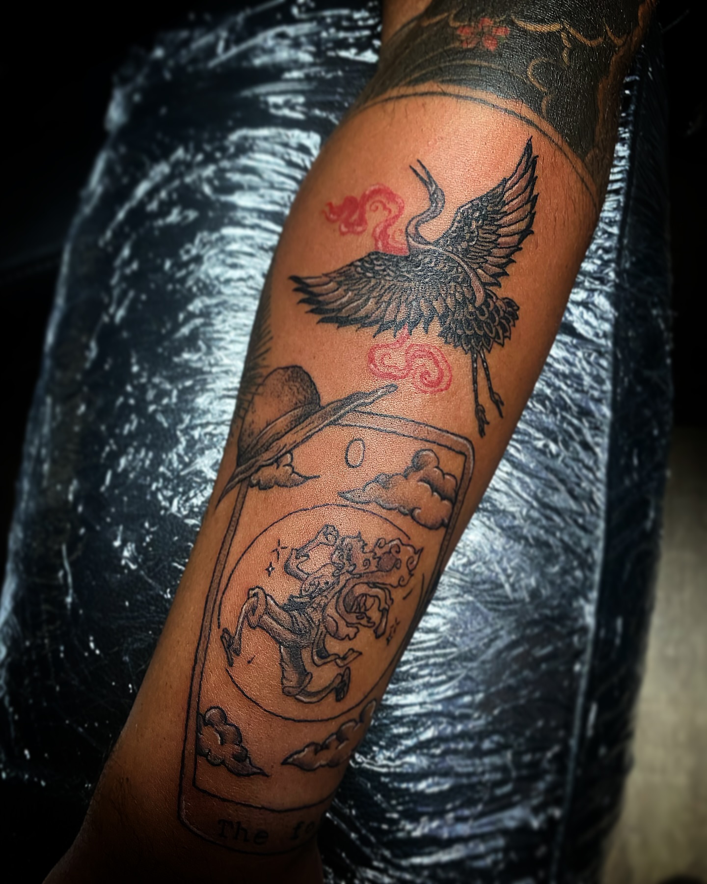 Bird and tarot card black and grey tattoo on the forearm by Rico Rosario