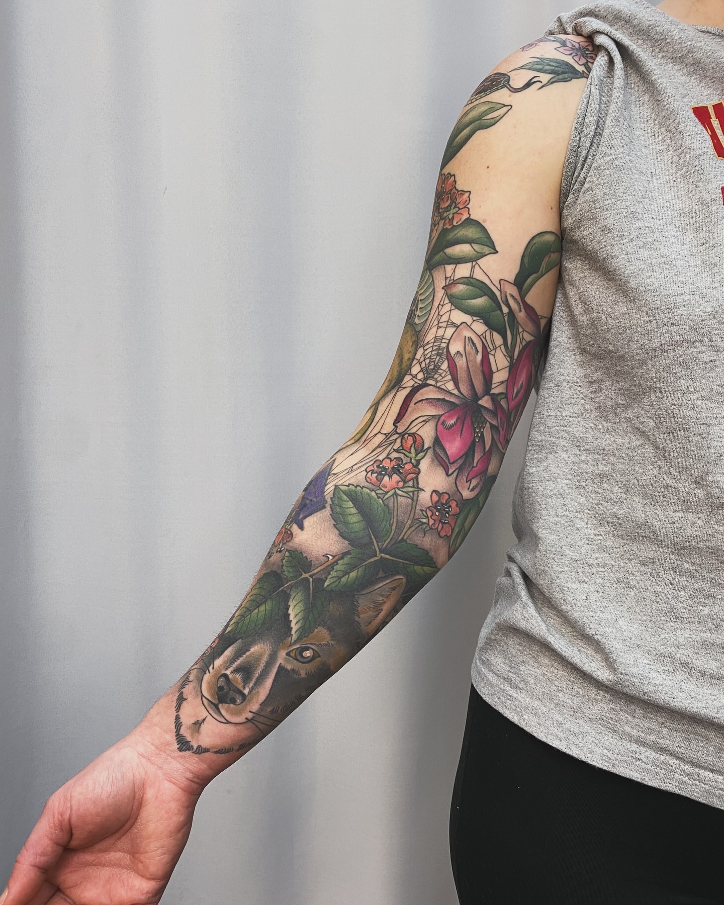 Wolf and flowers American traditional tattoo on the upper arm by Adam Bailey, Portland, Oregon