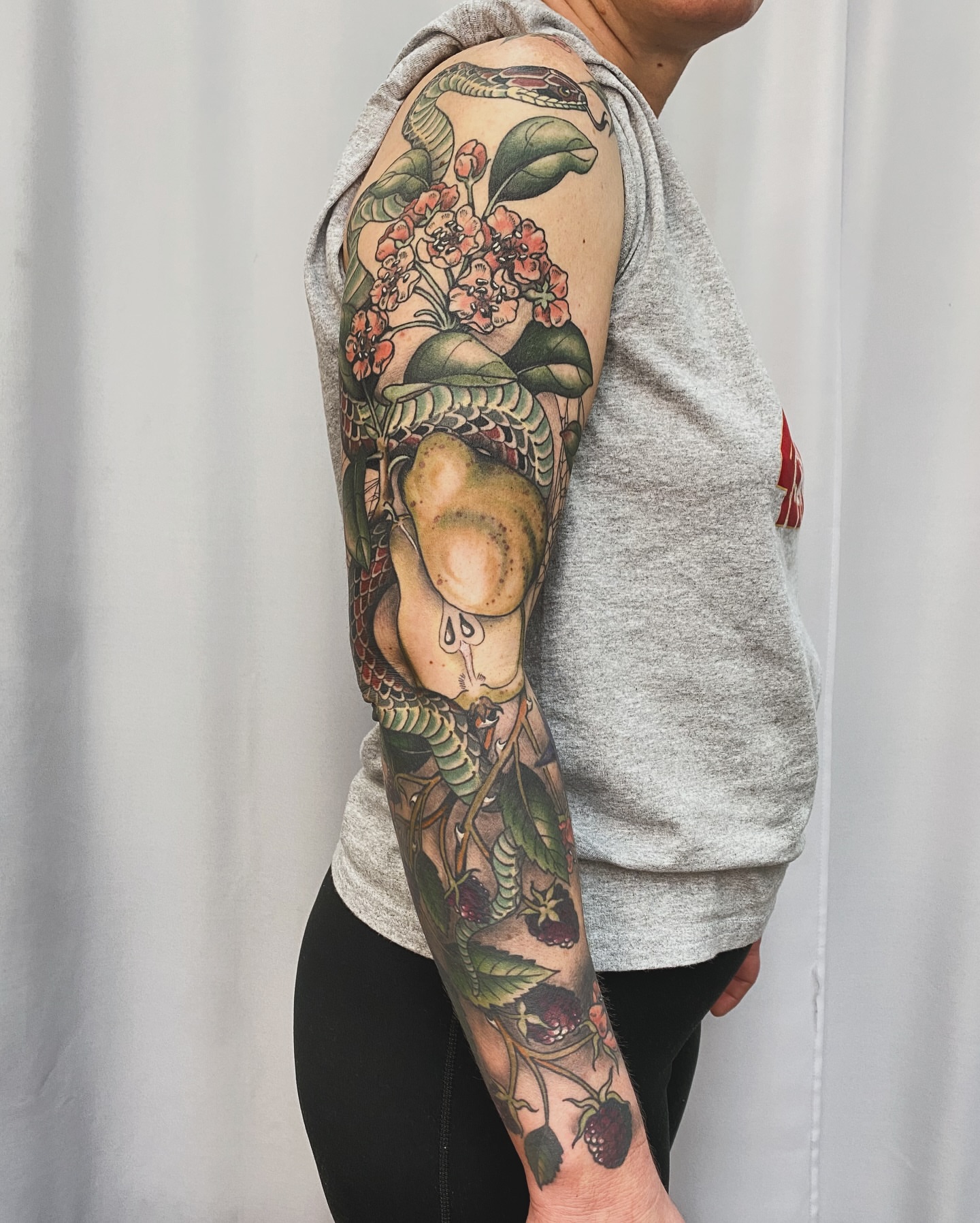Snake and flowers American traditional tattoo on the upper arm by Adam Bailey, Portland, Oregon