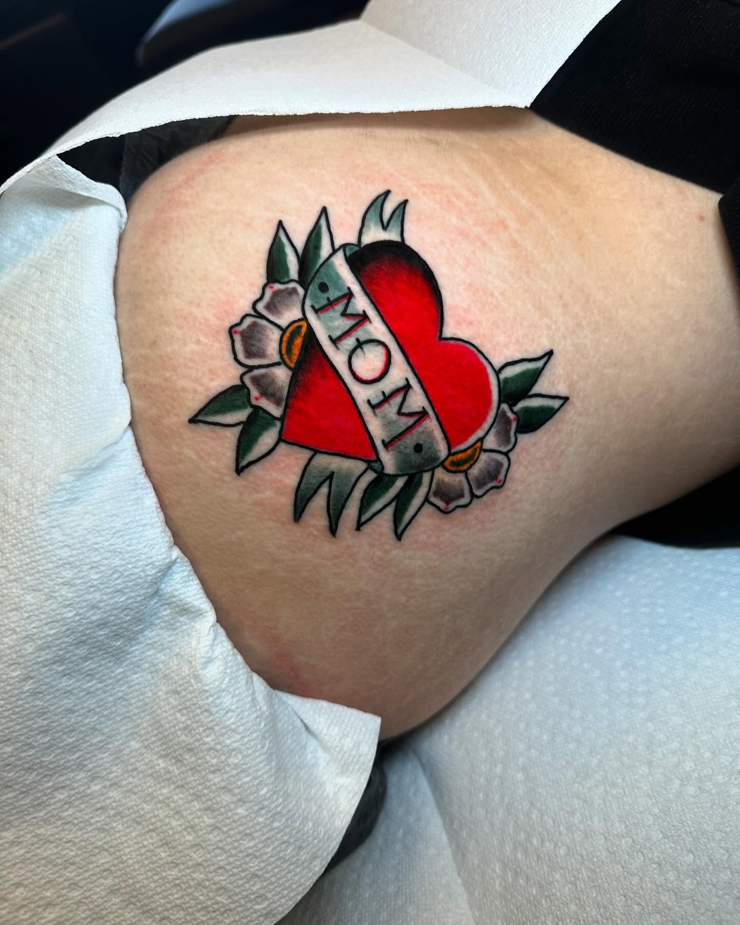 Heart with 'mom' banner American traditional tattoo on the thigh by Noah Diffenderfer, Phoenix, Arizona