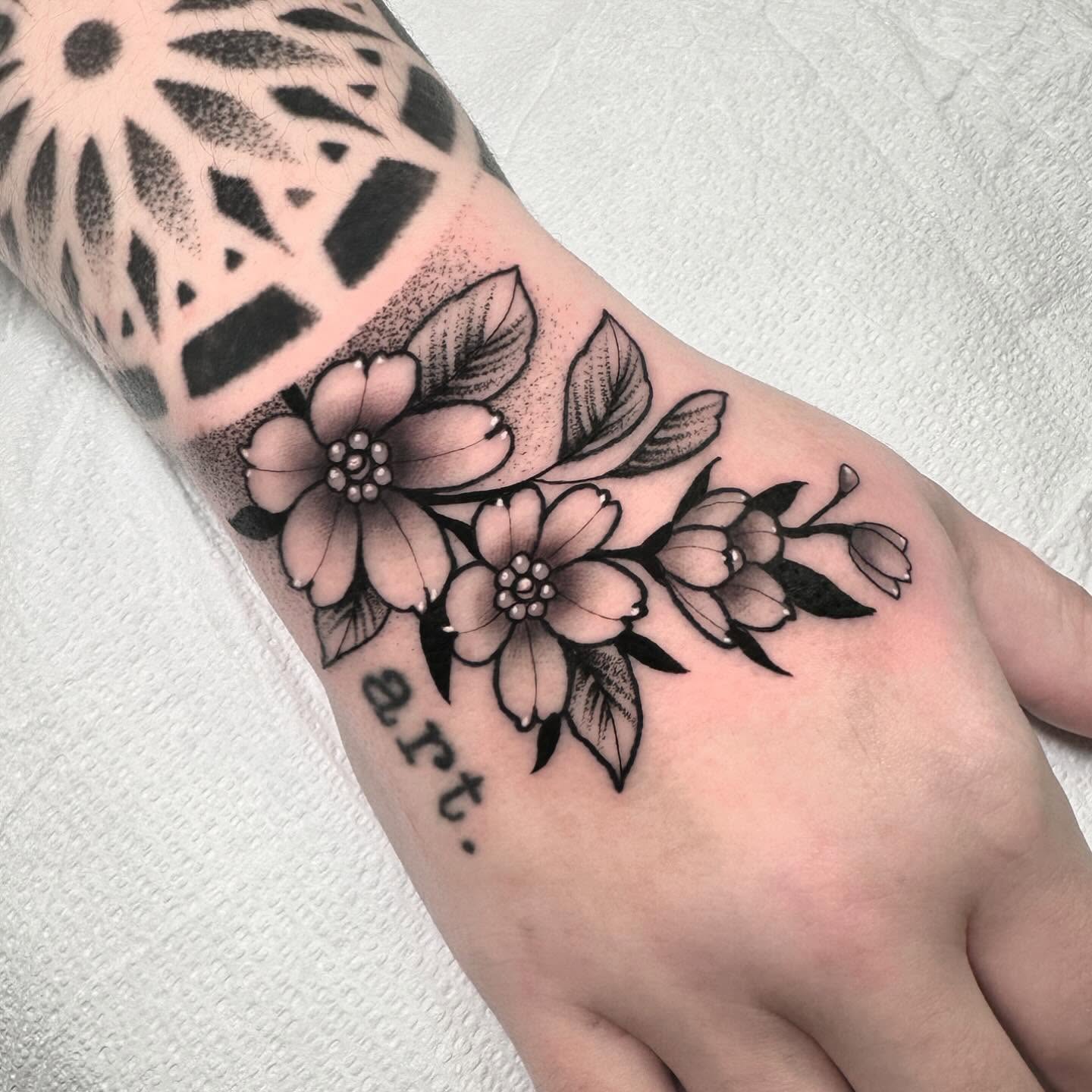 Flowers and leaves black and grey tattoo on the forearm by Patrick Whiting