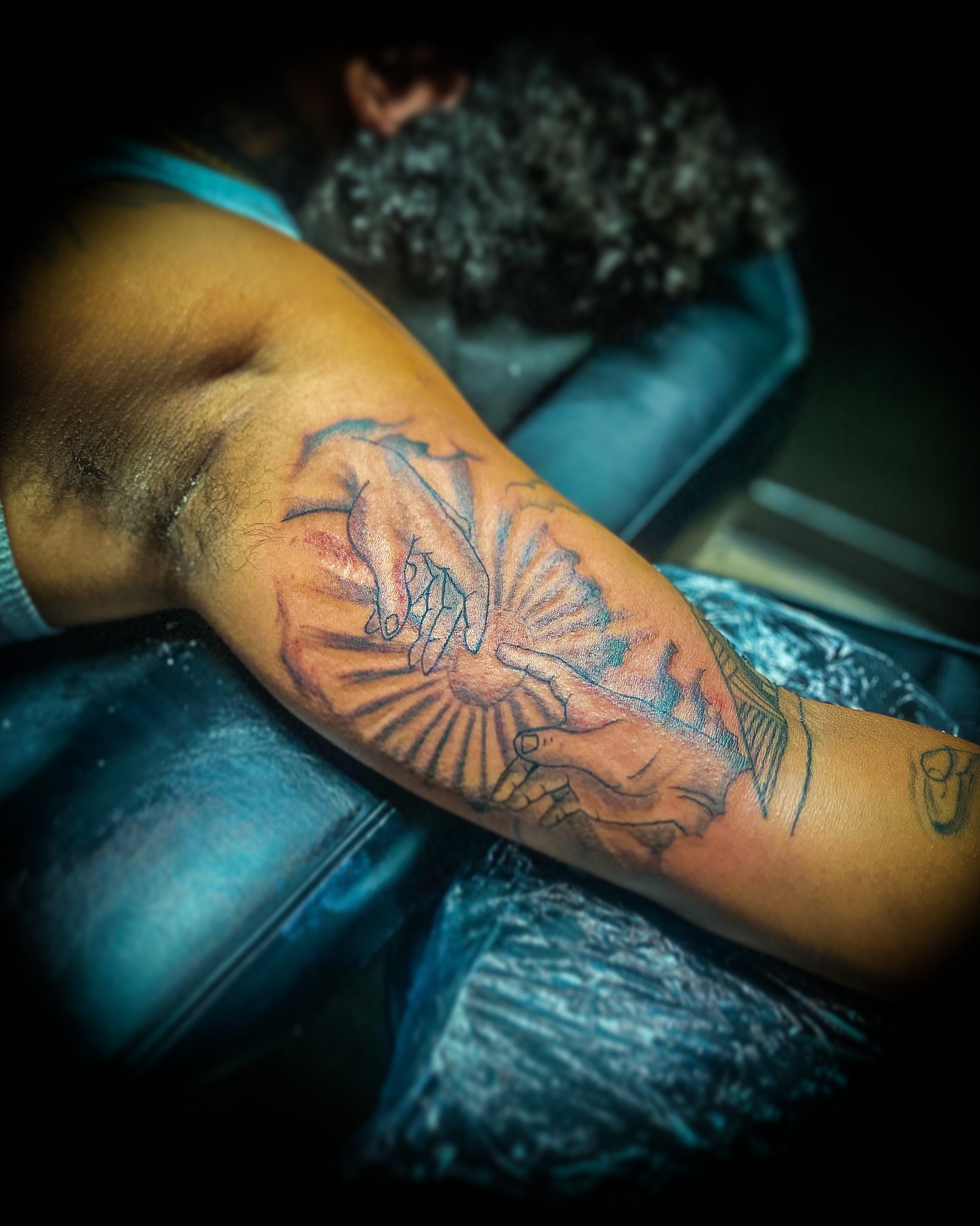 Hands and sunburst American traditional tattoo on the forearm by Rico Rosario