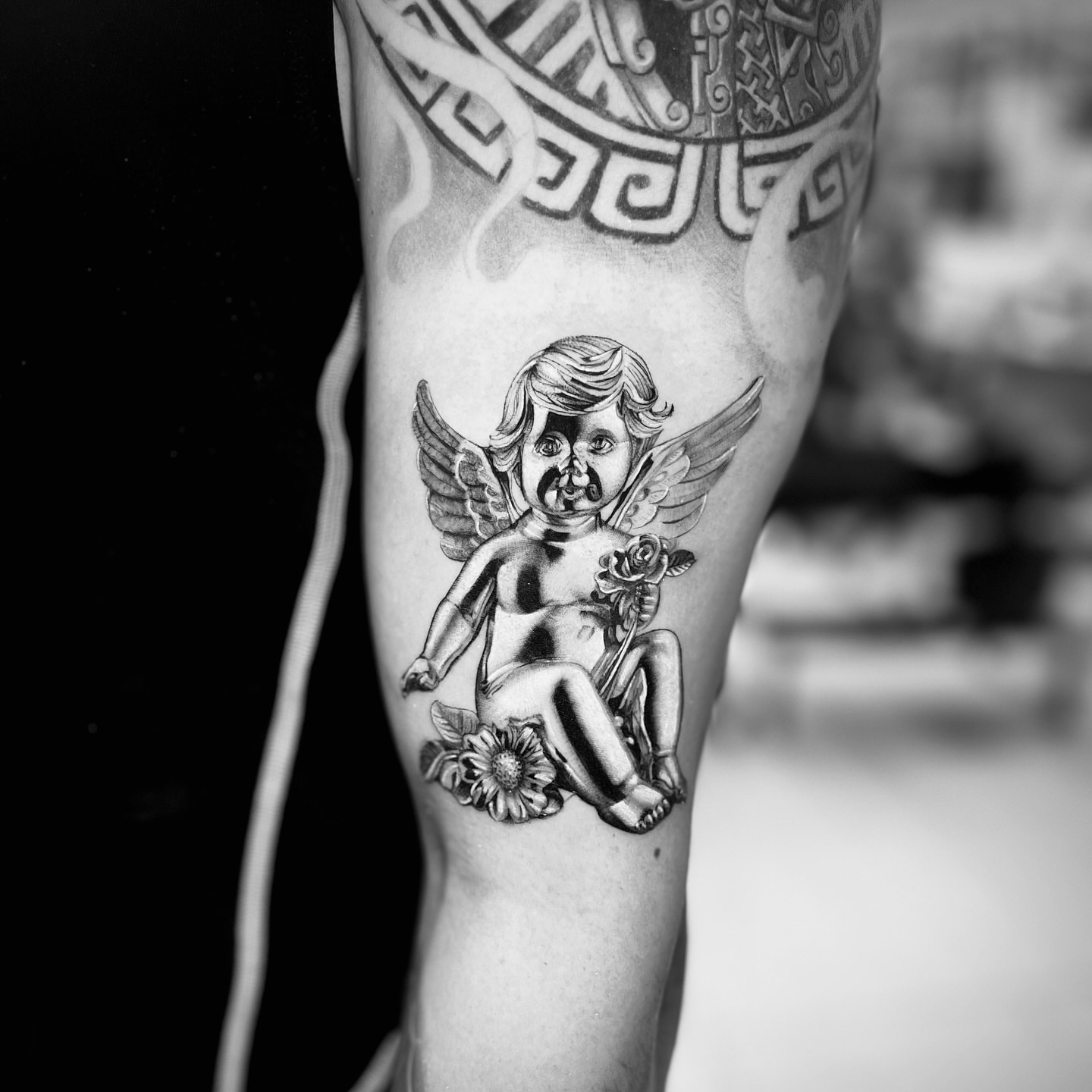 Cherub with flowers black and grey tattoo on the forearm by Bay Area Tattoo Artist