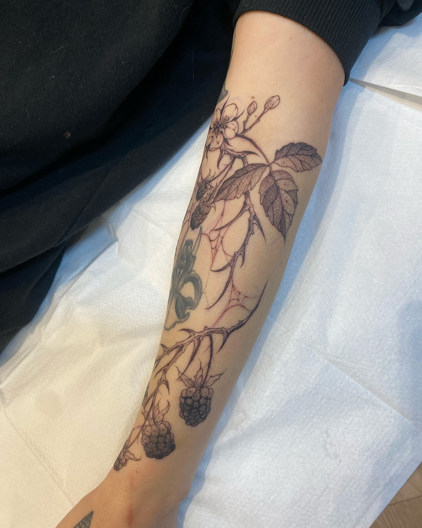 Flower and berries black and grey tattoo on the forearm by Becci Chelicerata